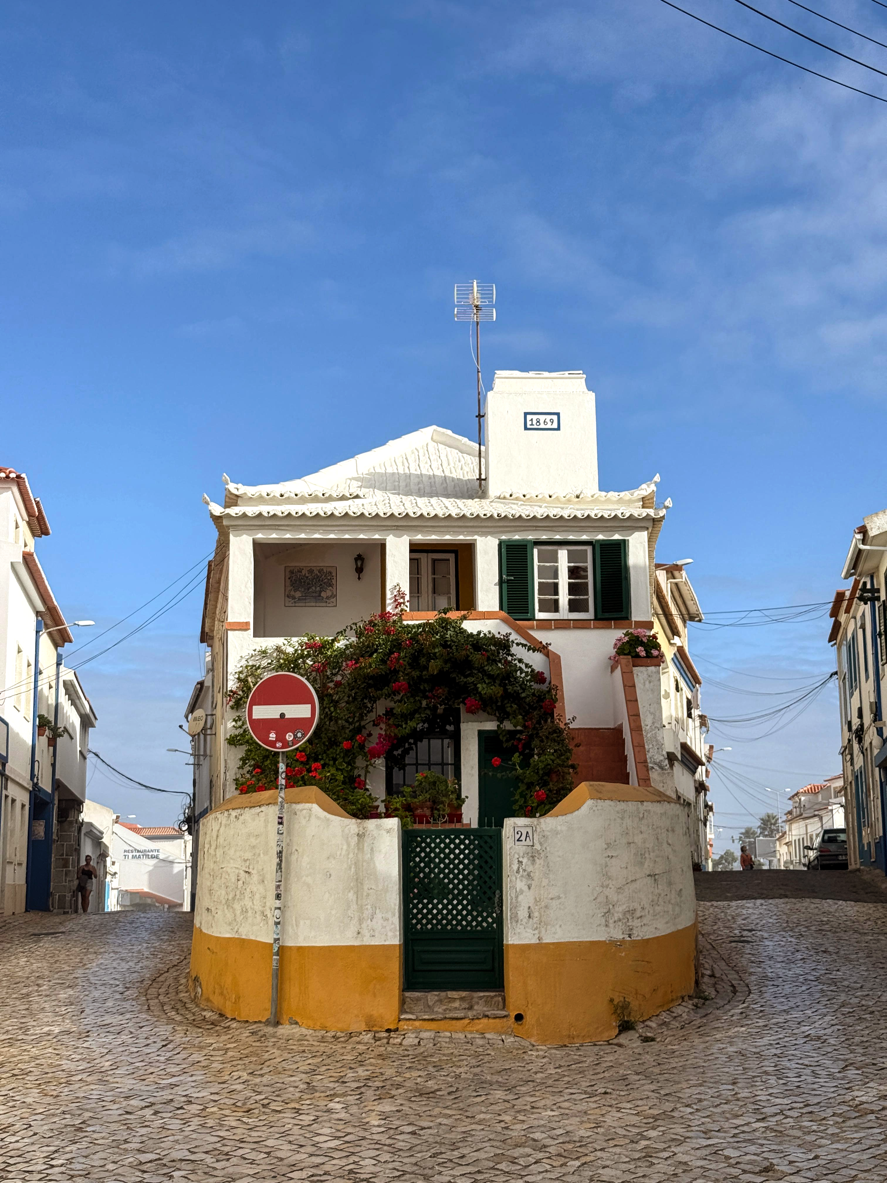 Whitewashed corner house with bougainvillea on a cobbled street, Portugal