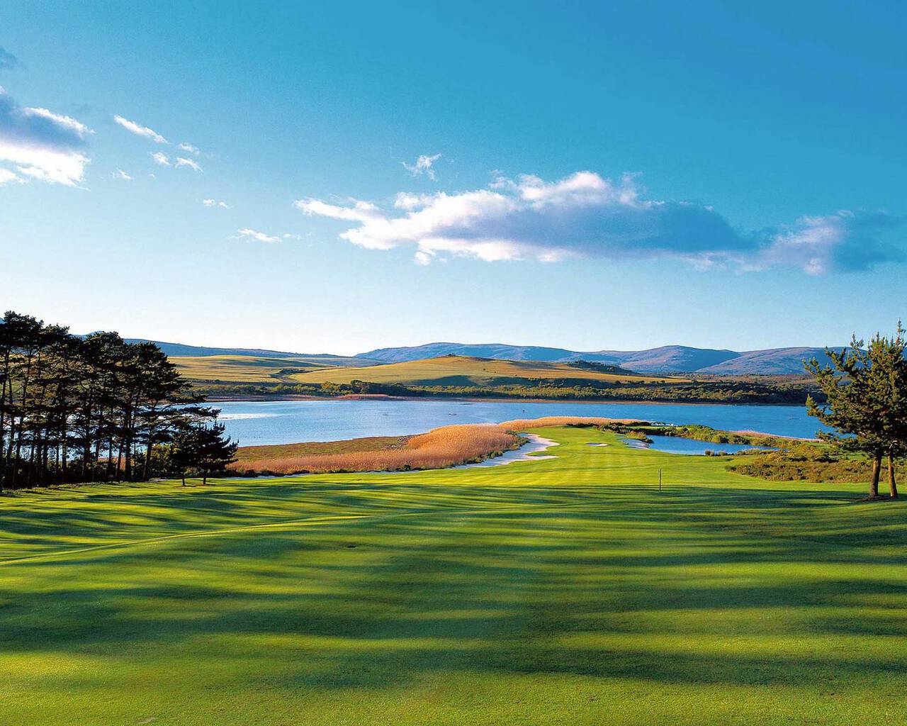 Arabella Golf Course fairway leading to a lagoon with mountains beyond