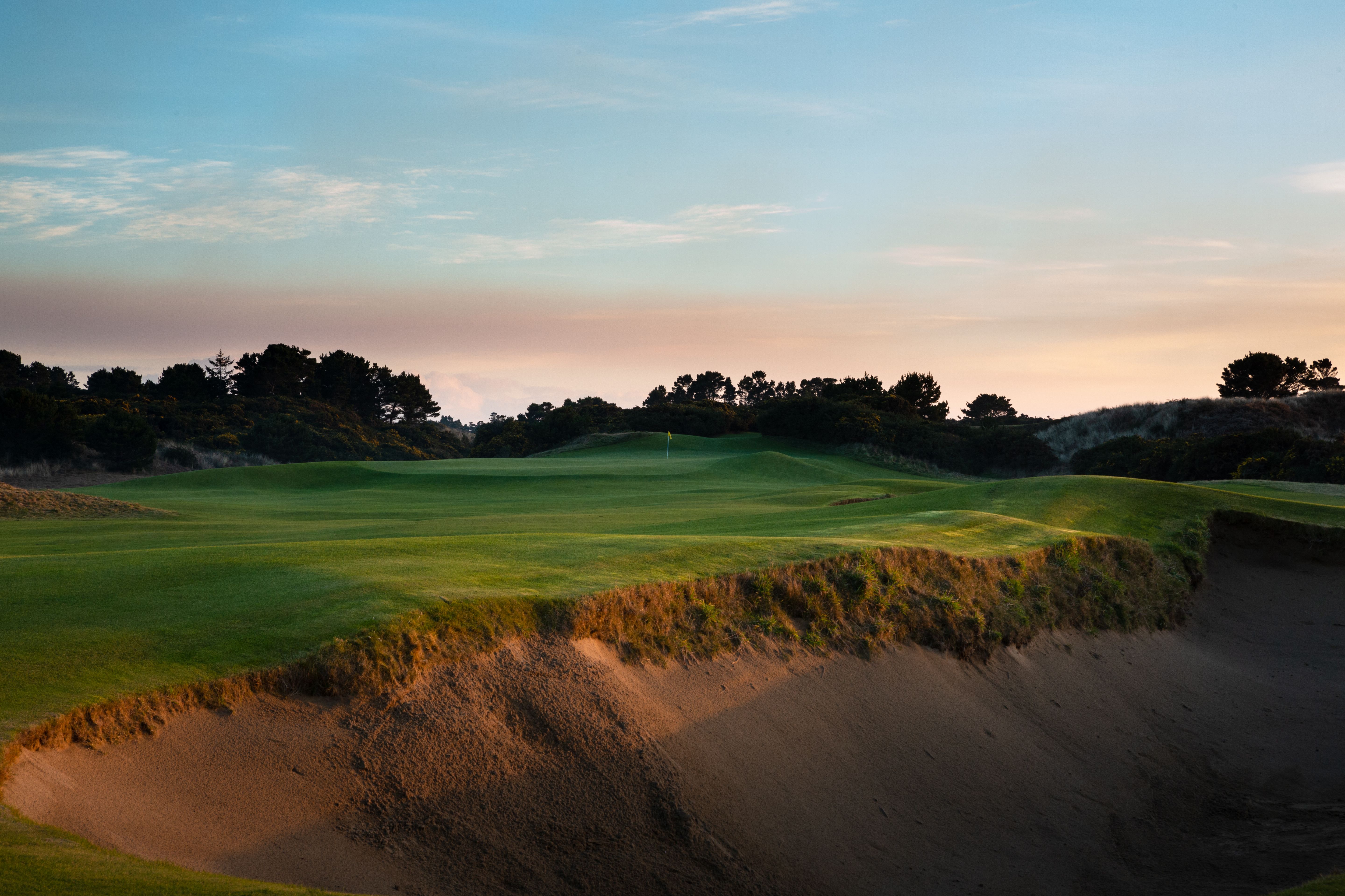 Pacific Dunes green above a deep sand bunker at sunset