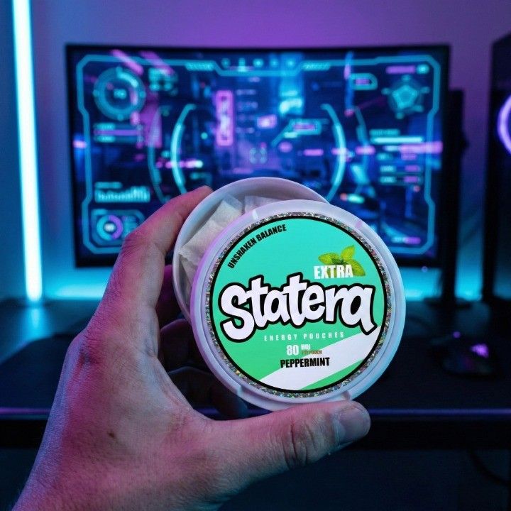 Gamer holding STATERA energy pouch tin in front of computer screen