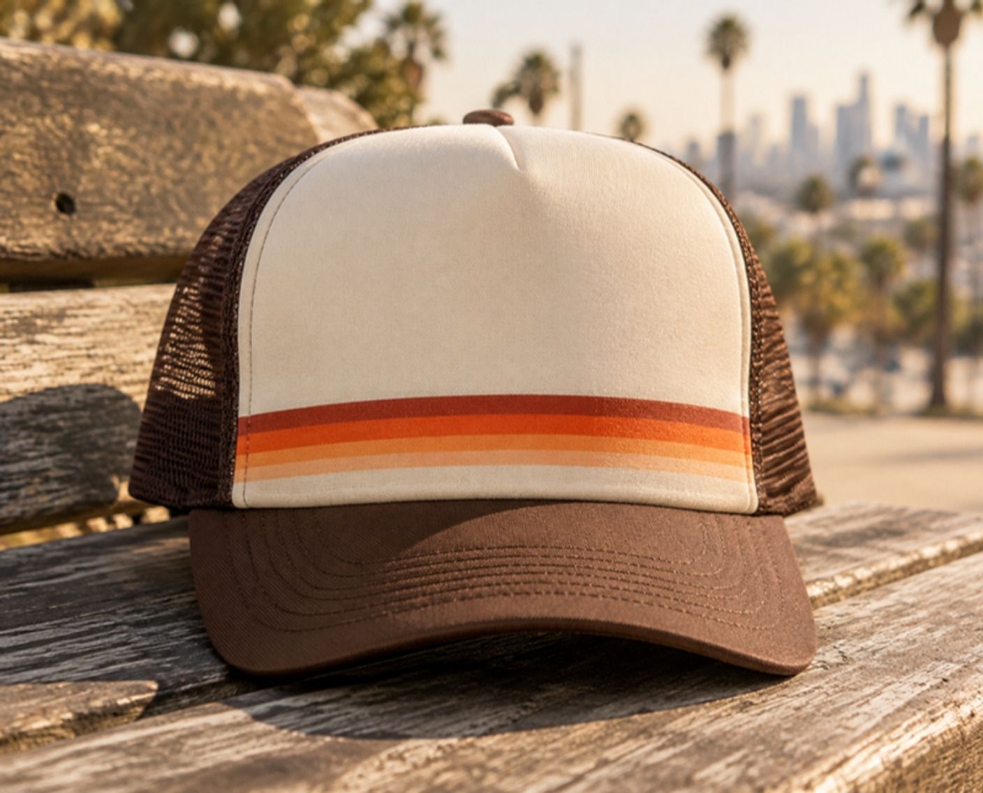 Cream and brown trucker hat with a retro stripe, on a bench with the LA skyline behind