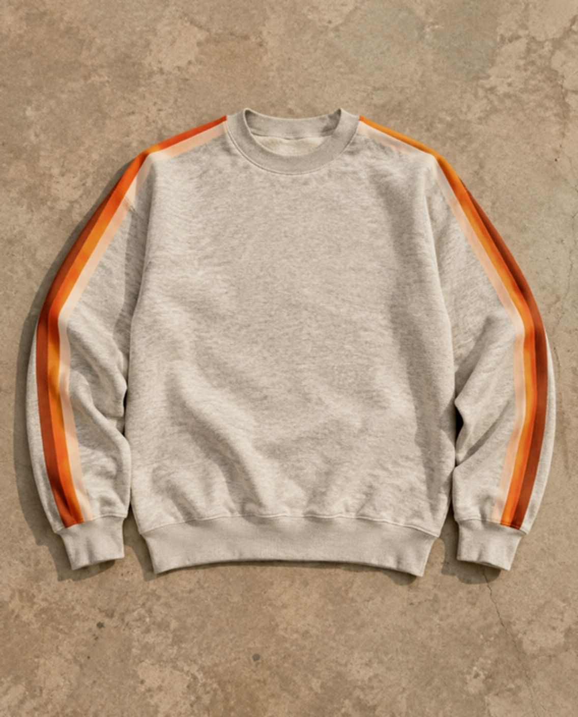 Oatmeal crewneck with retro stripes down both sleeves, laid flat on concrete