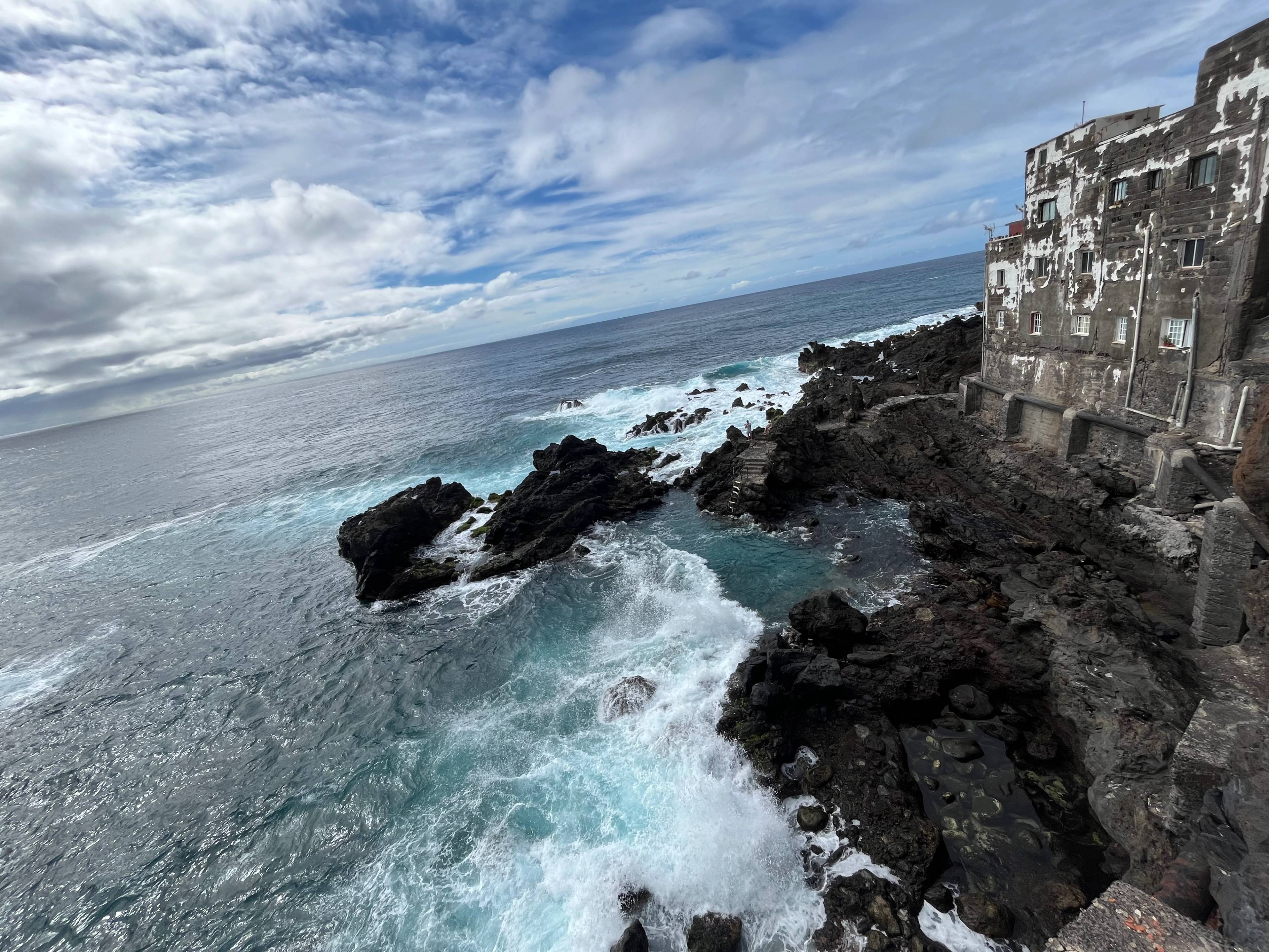 Ciemna kamienica stojąca tuż przy oceanie, mnóstwo skał i woda
