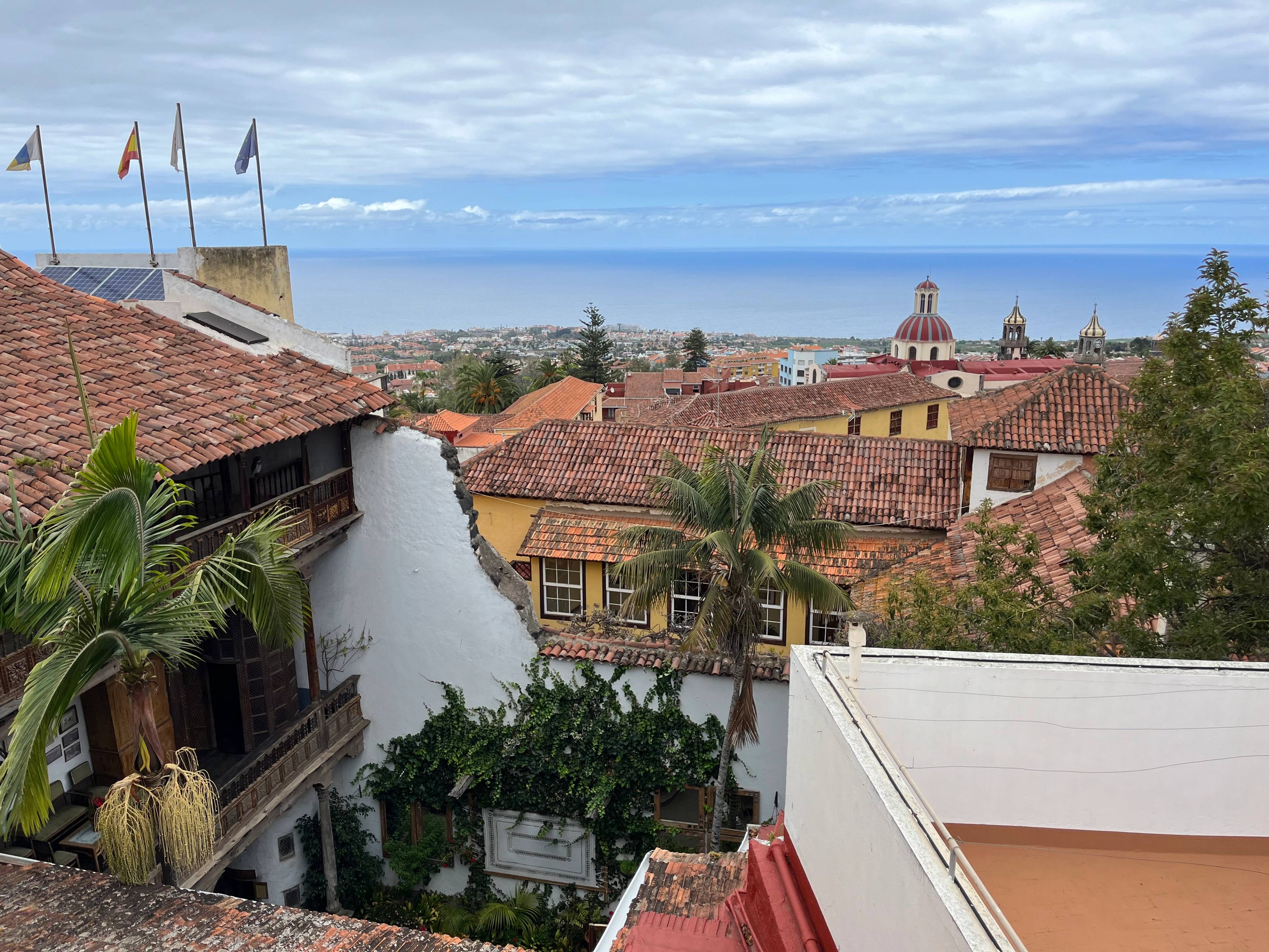 Widok na czerwone dachy i kolonialne budynki La Orotava z widoczną kopułą kościoła w tle.