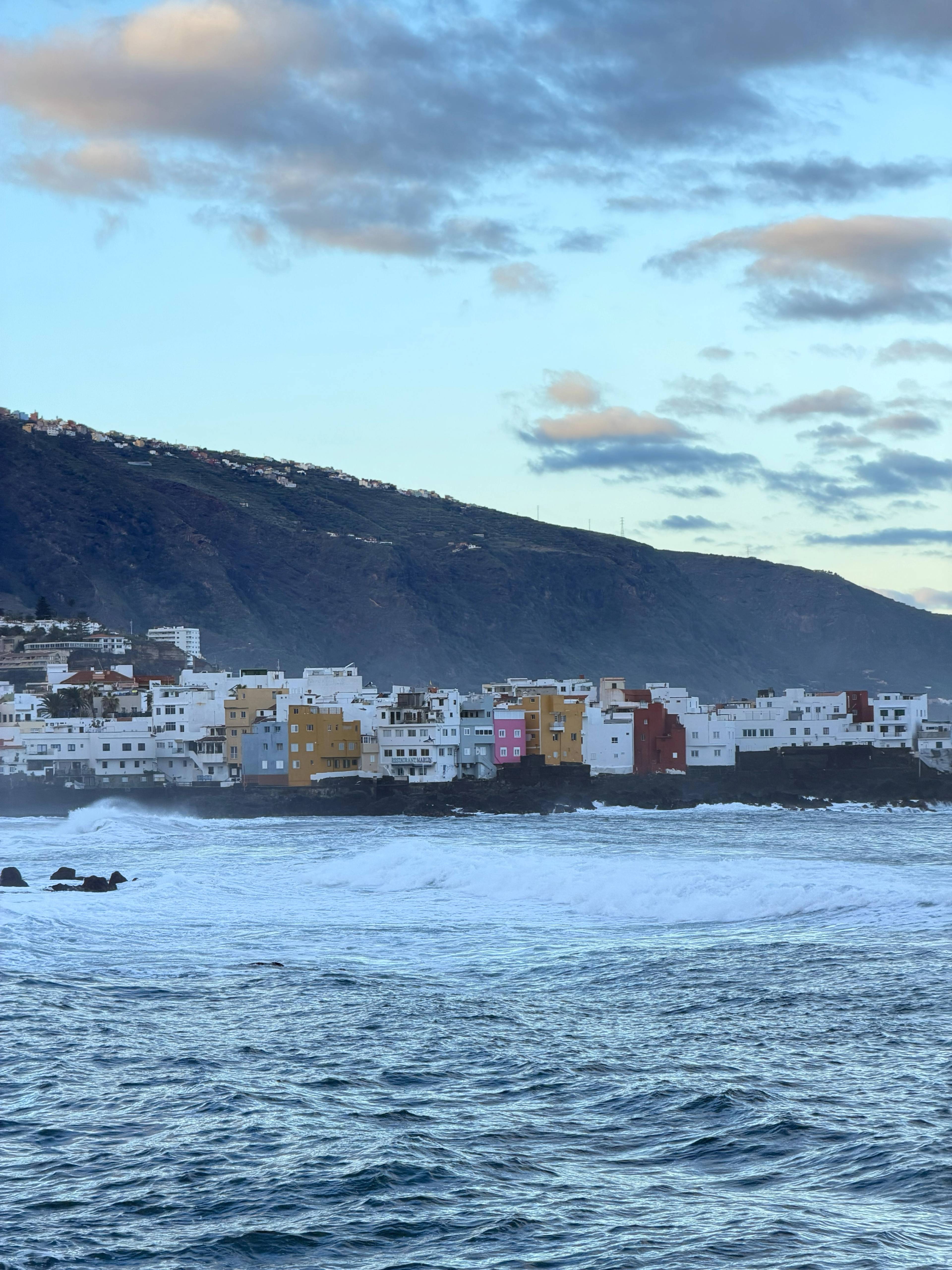 Widok na port z łodziami i zabudowaniami nad wodą.