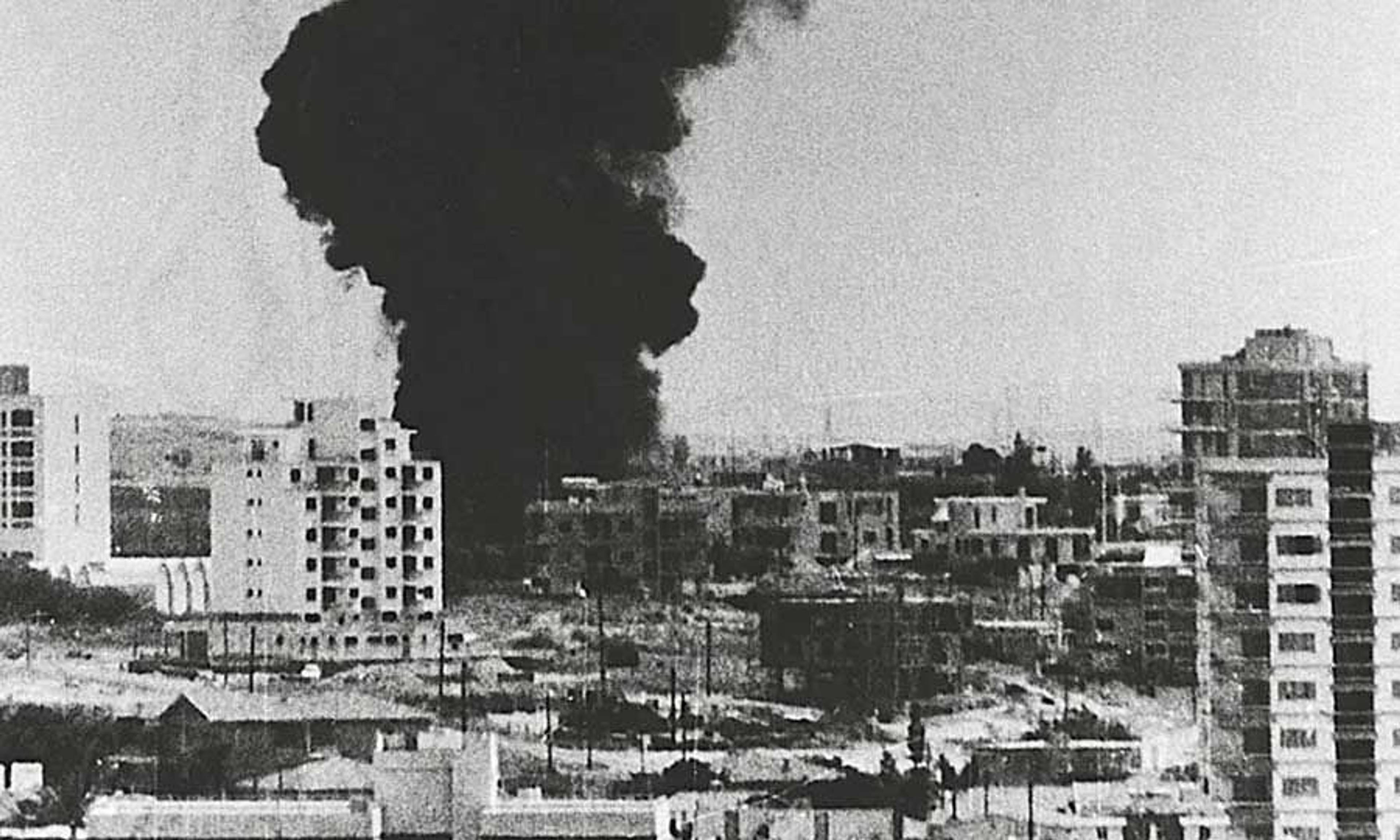 Miasto podczas bombardowania, widoczne bloki i chmura czarnego dymu