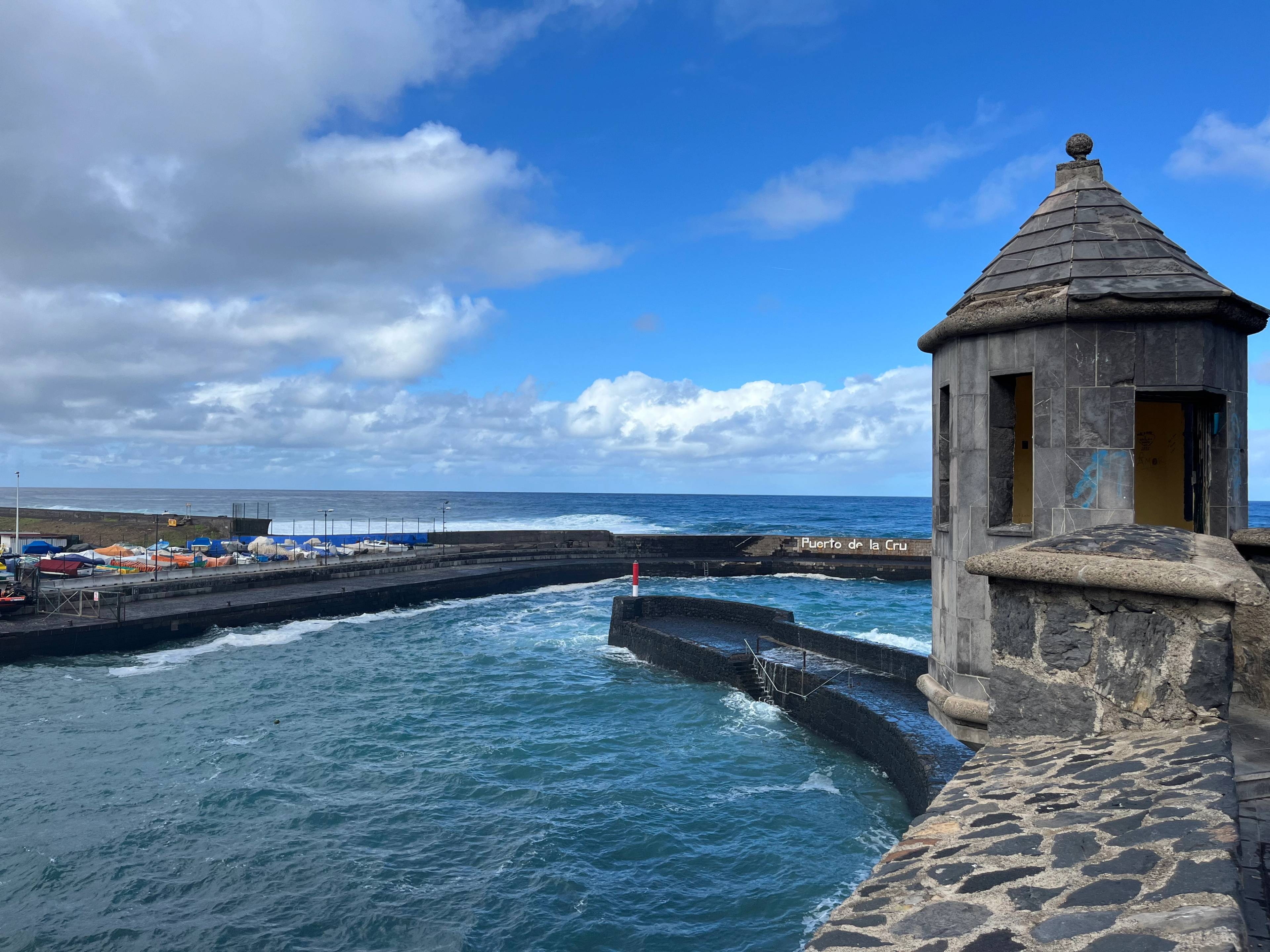 Kamienna wieżyczka przy nabrzeżu z widokiem na ocean i błękitne niebo.