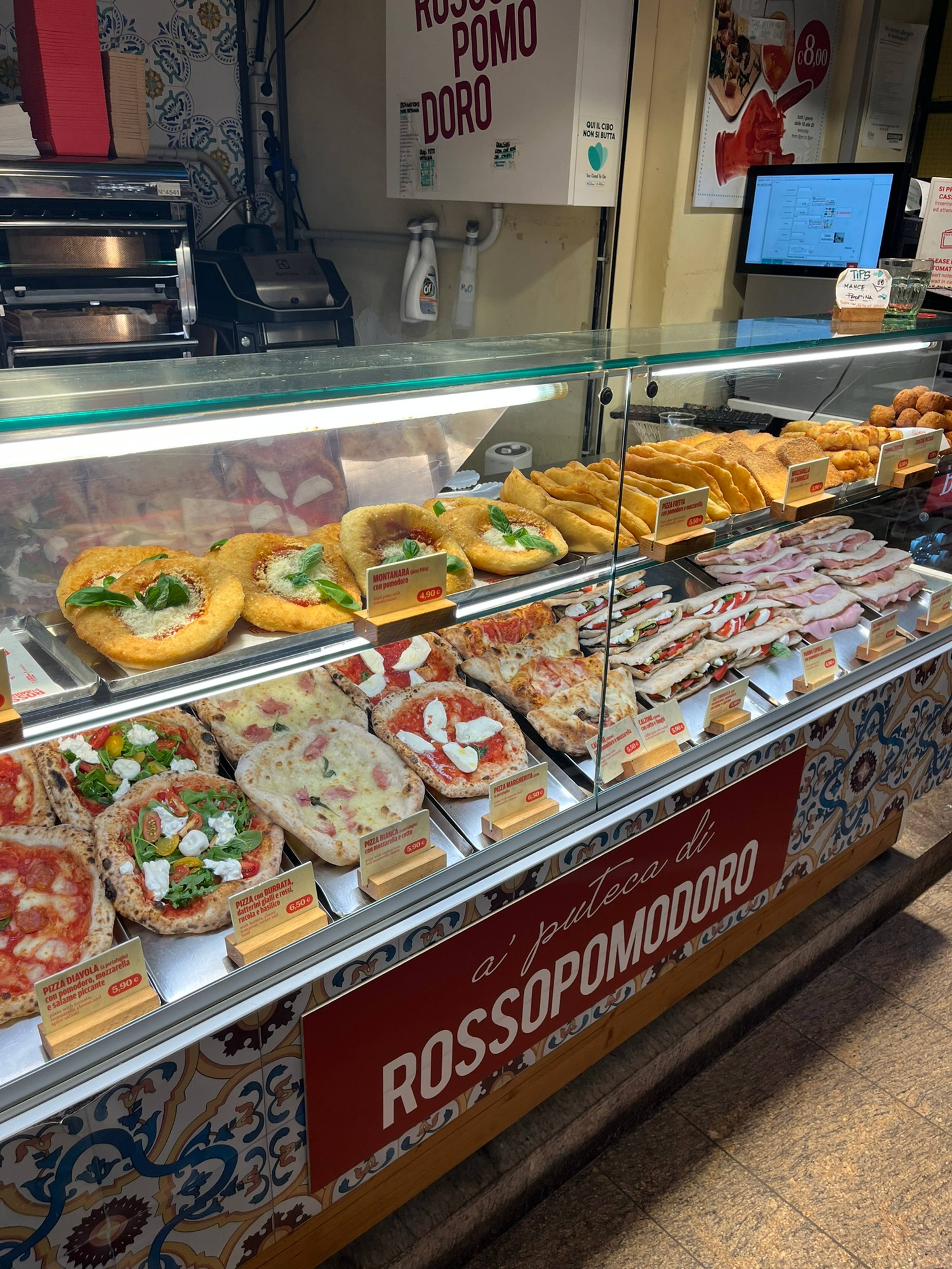Lodówka wypełniona mini pizzami i kanapkami typu panini.