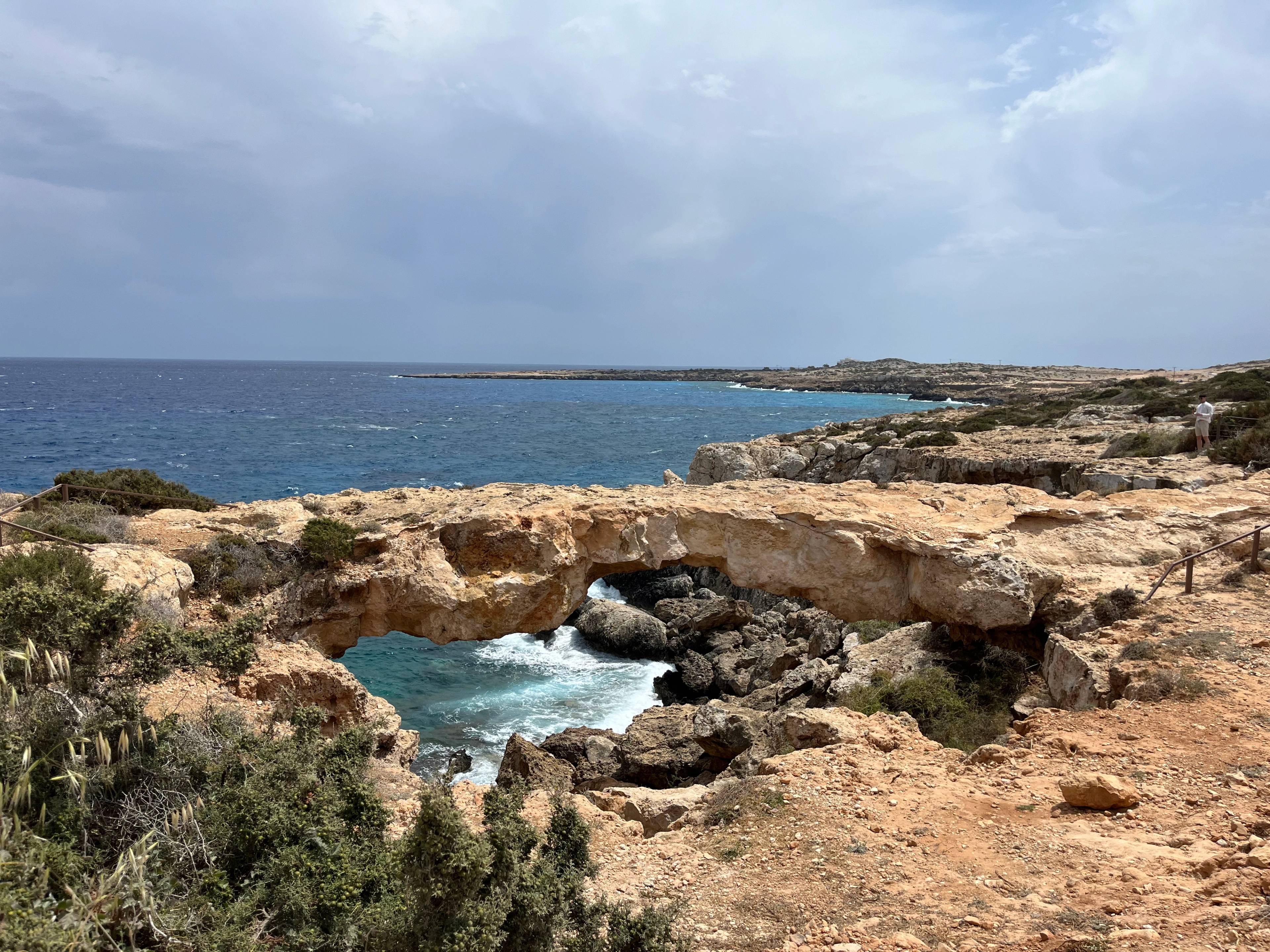 Naturalny skalny łuk nad morzem w Protaras na Cyprze, otoczony surowym, skalistym krajobrazem.