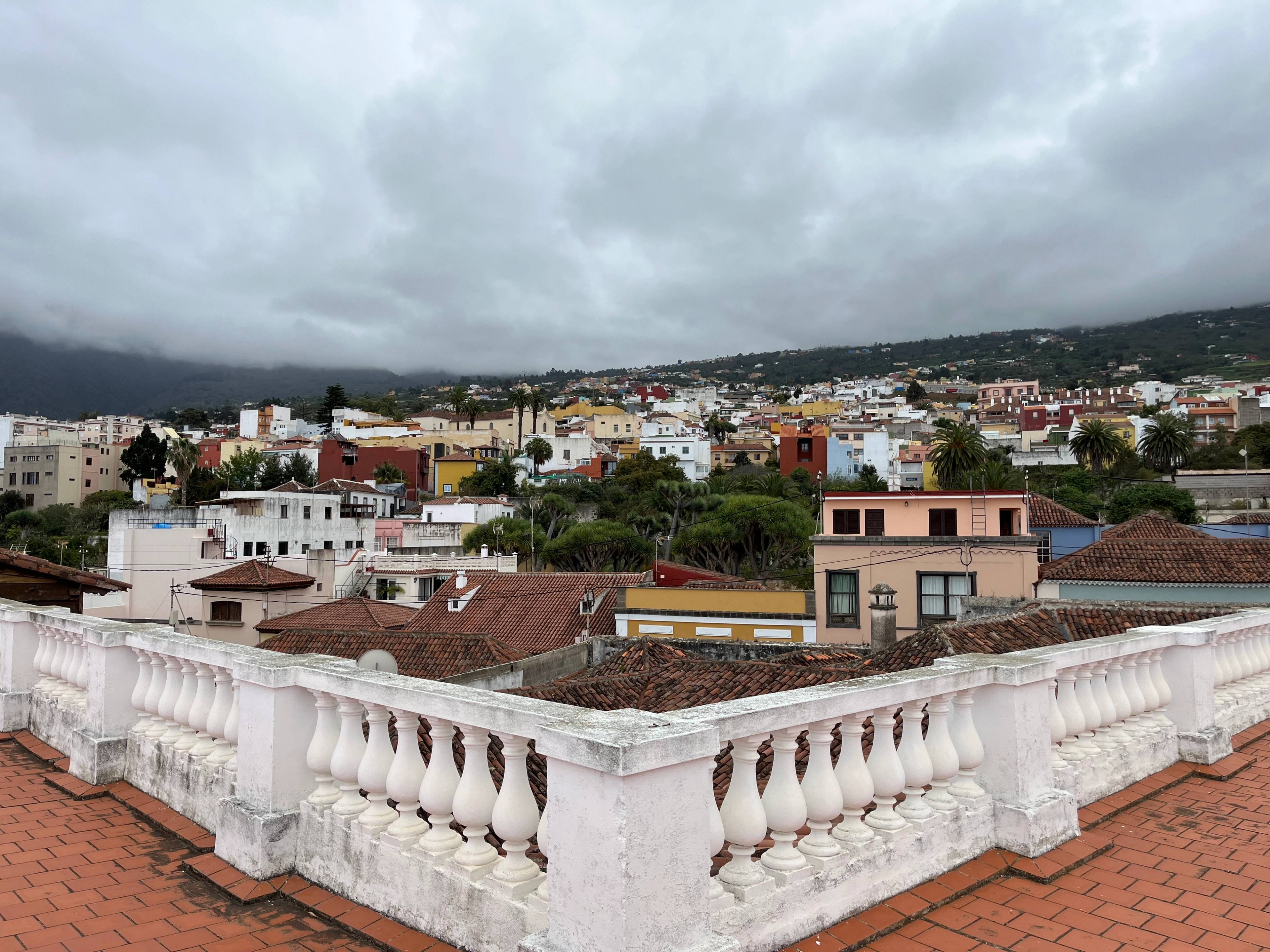 Panorama La Orotava widziana z tarasu z białą balustradą i czerwonymi dachami budynków.