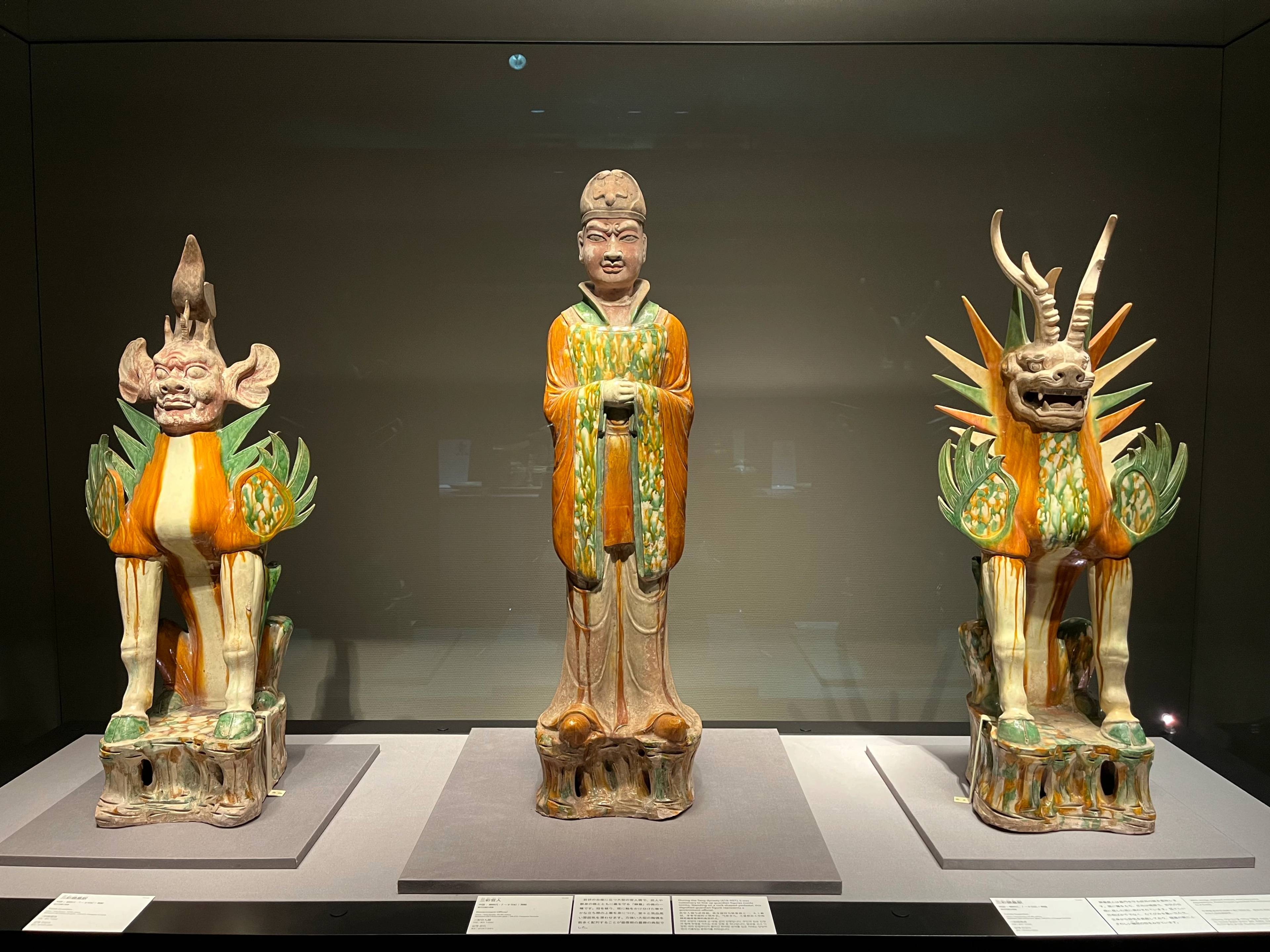 Zabytkowe rzeźby ceramiczne w muzeum, przedstawiające postać oraz fantastyczne zwierzęta ustawione na ekspozycji.