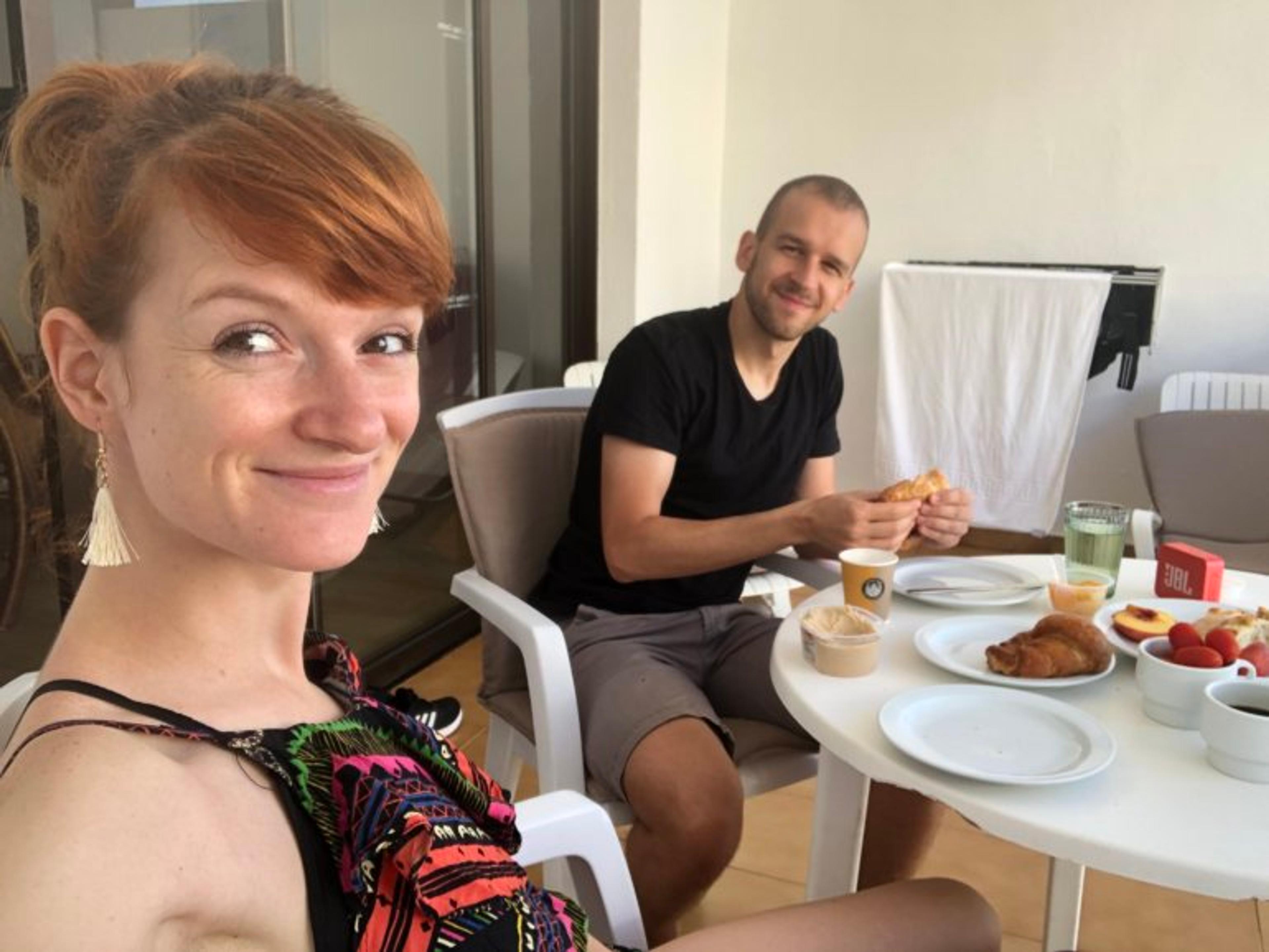 Uśmiechnięta para na krzesłach na balkonie podczas śniadania