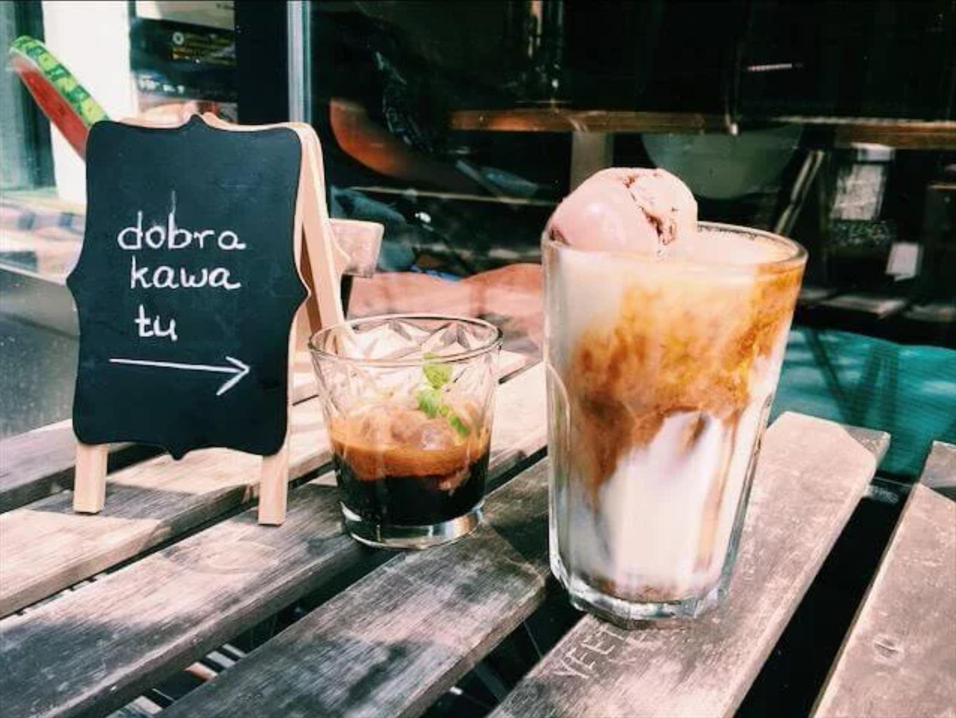Kawa z lodami oraz druga espresso na stoliku obok napis "dobra kawa tu"