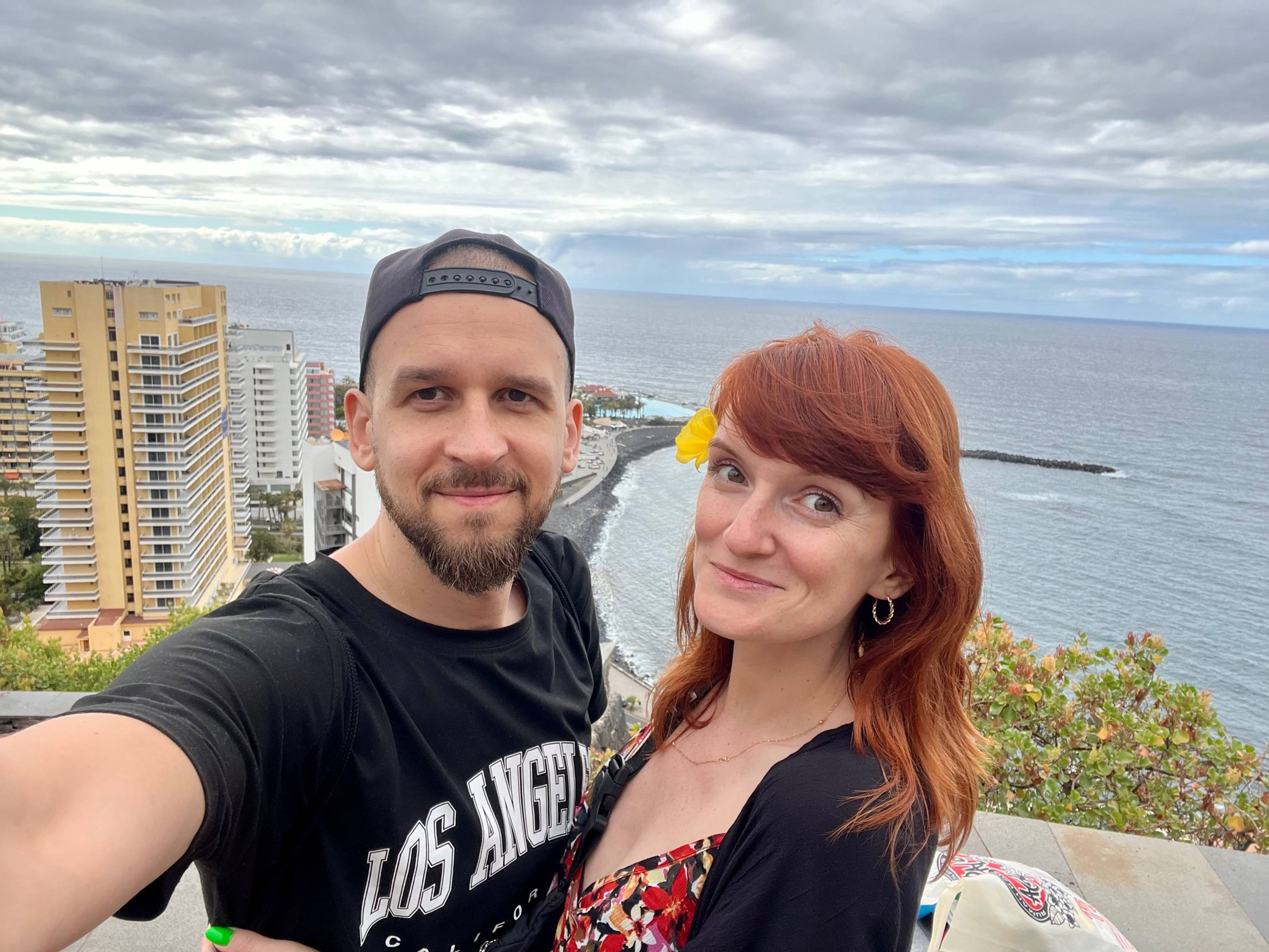 Mężczyzna i kobieta pozują na tle panoramy miasta i oceanu.