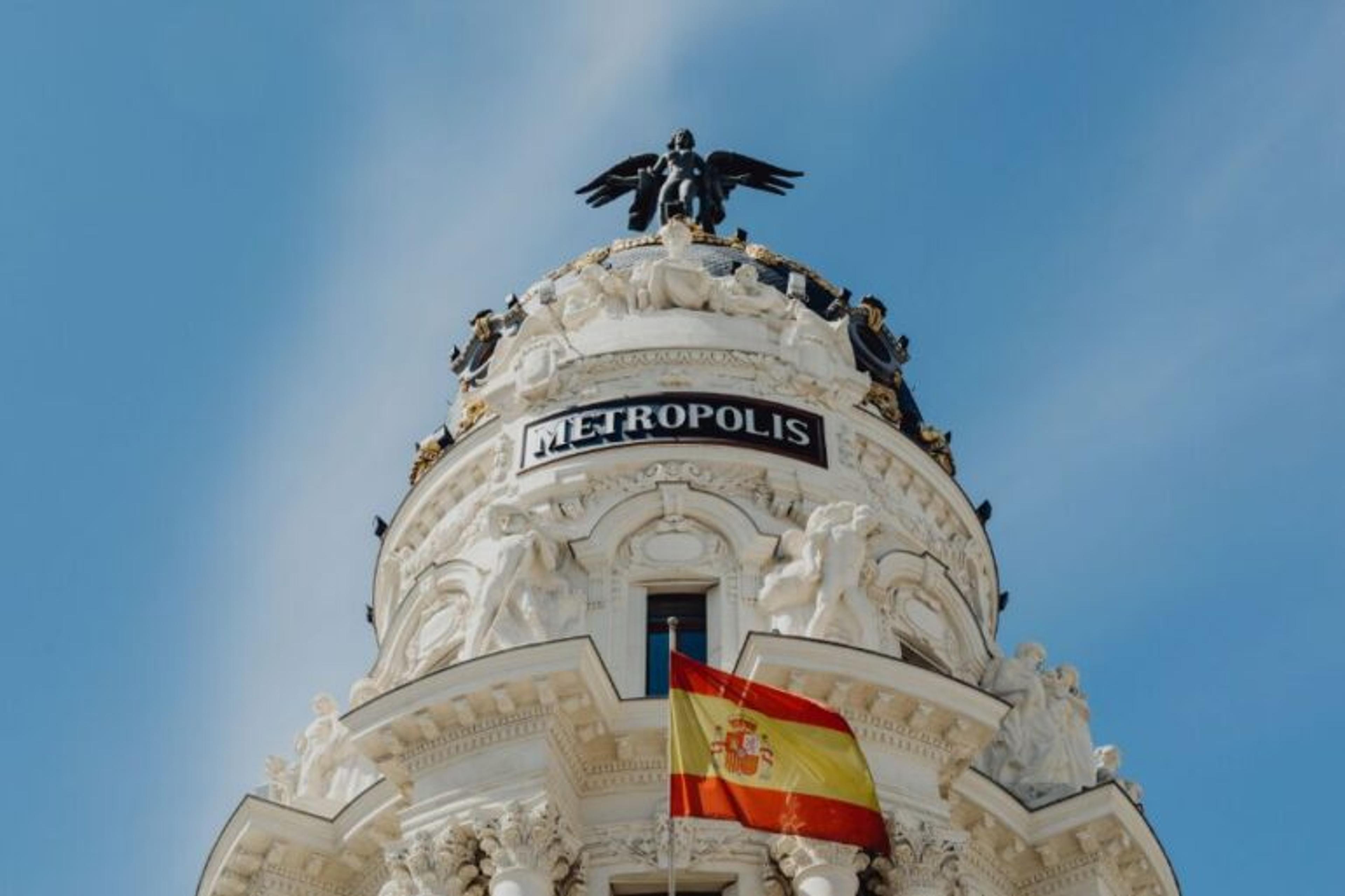 Budynek Metropolis, flaga Hiszpanii, posąg orła na szczycie