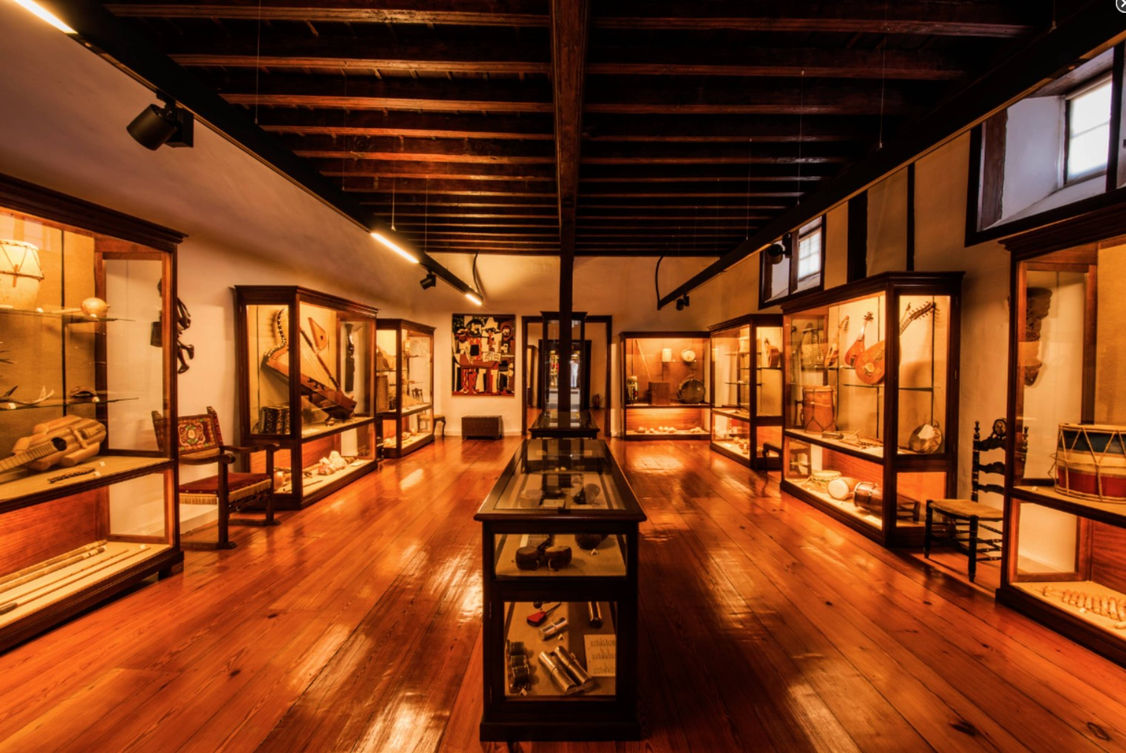 Sala muzealna w La Orotava prezentująca tradycyjne instrumenty, narzędzia i lokalne wyroby w elegancko oświetlonych gablotach.