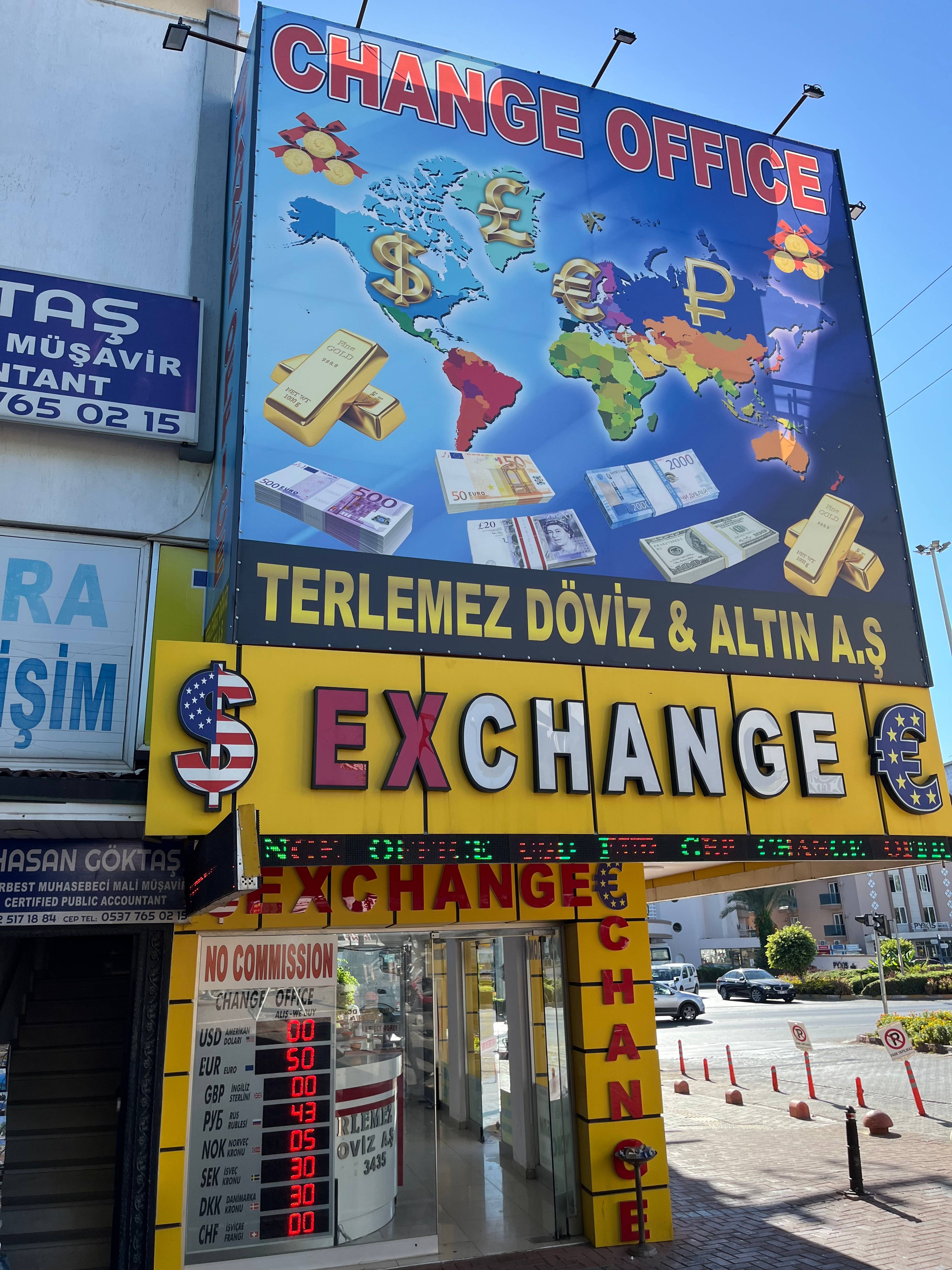 Tablica kantoru wymiany walut z napisem „Exchange” i kolorowymi grafikami banknotów.