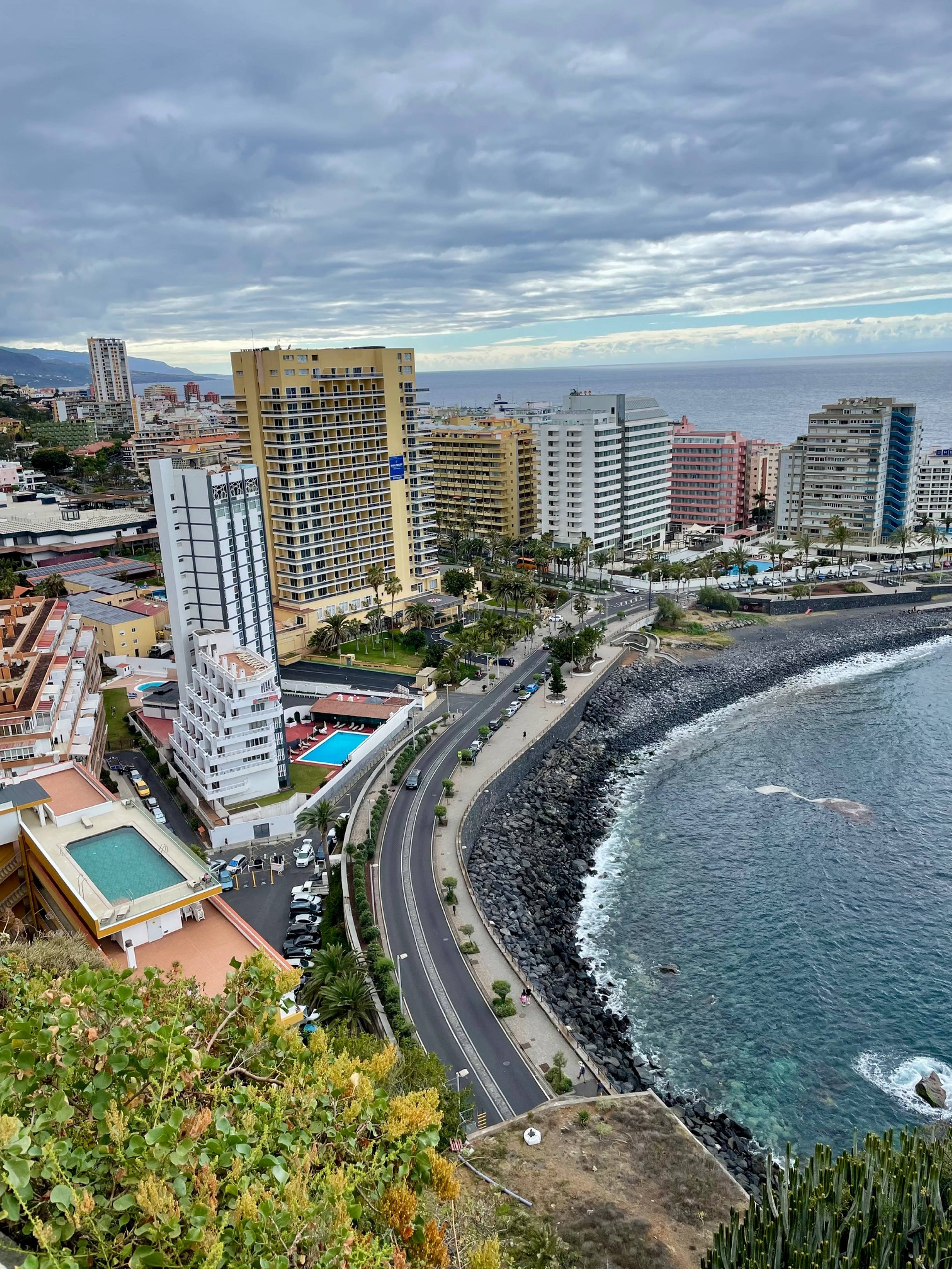 Widok nadmorskiego miasta z wysokimi budynkami i oceanem w tle.