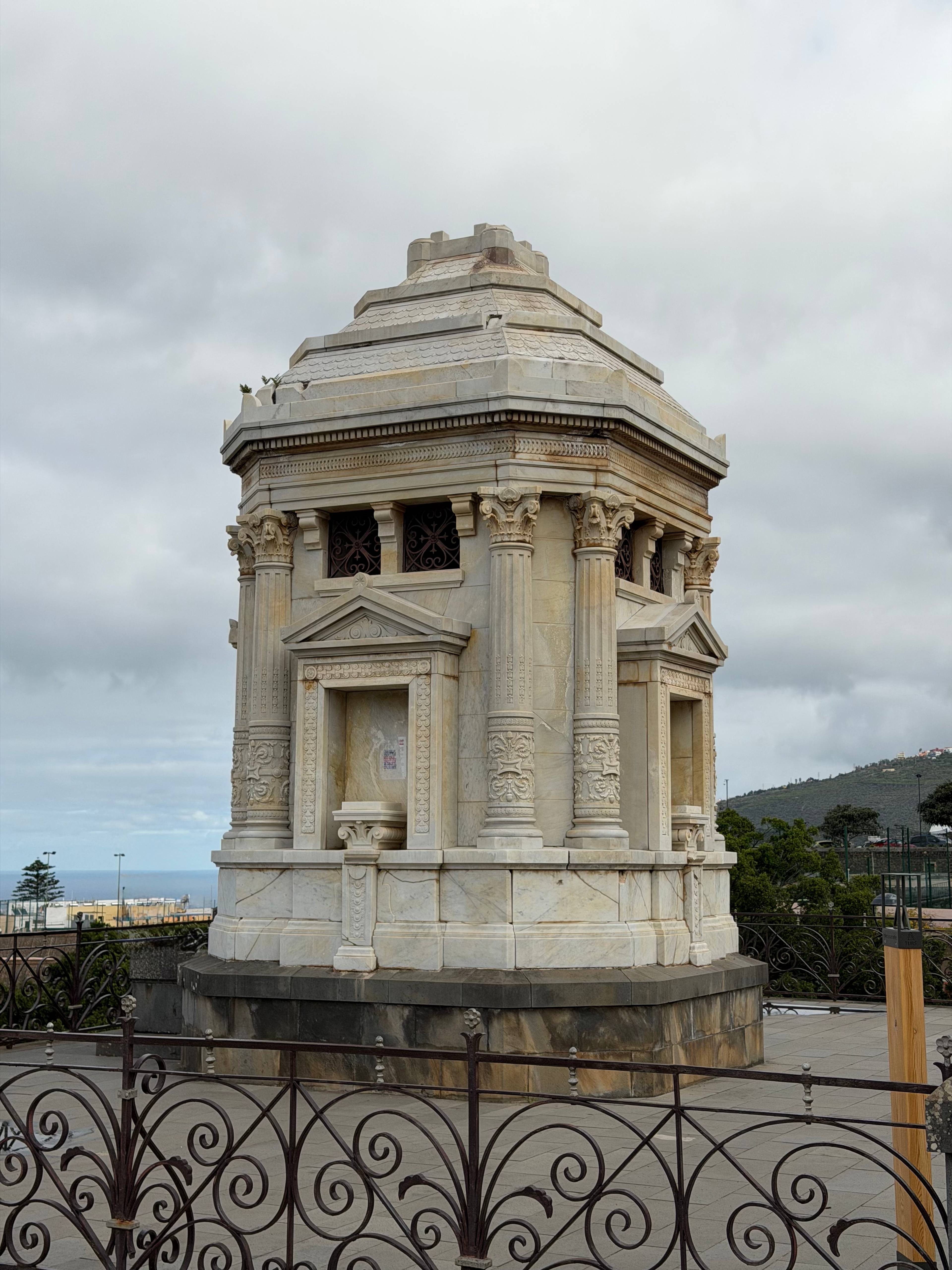Białe marmurowe mauzoleum na tle pochmurnego nieba w ogrodach w La Orotava.