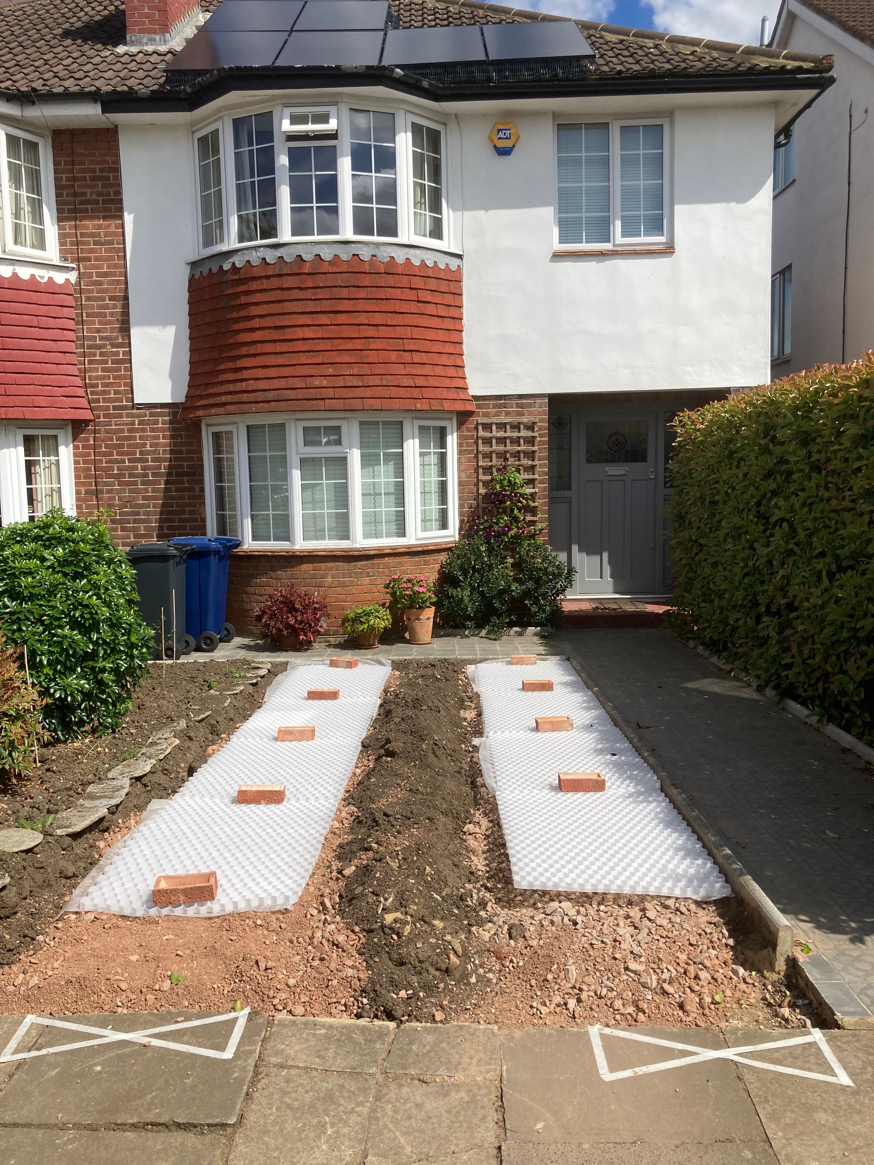 A front garden being prepared to support a parked electric car