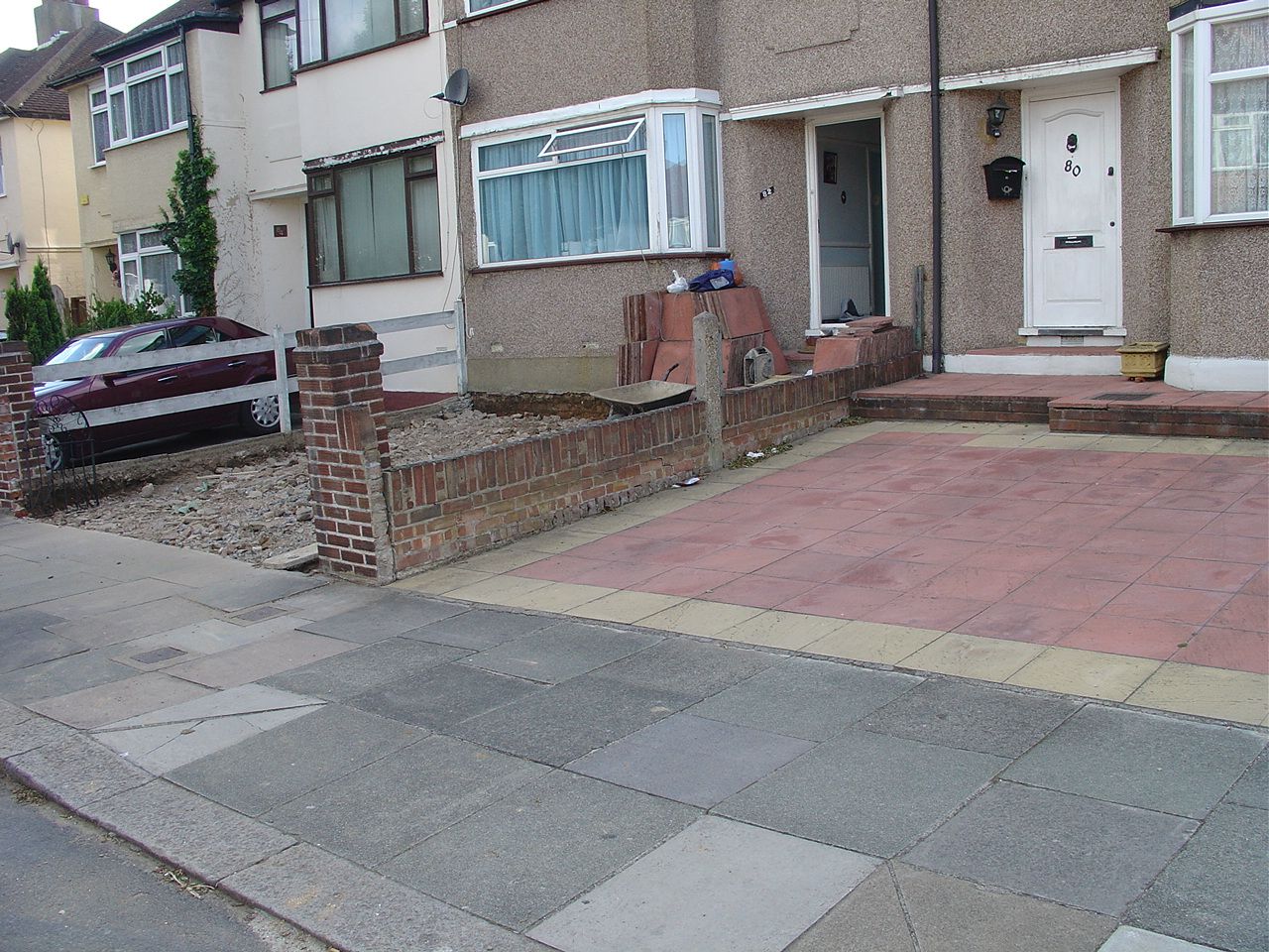 Photo of a totally paved front garden in Northolt, with no plants at all,  no provision for run-off so adds to flood risk (rain runs straight into the road) and lack of wall removes privacy  