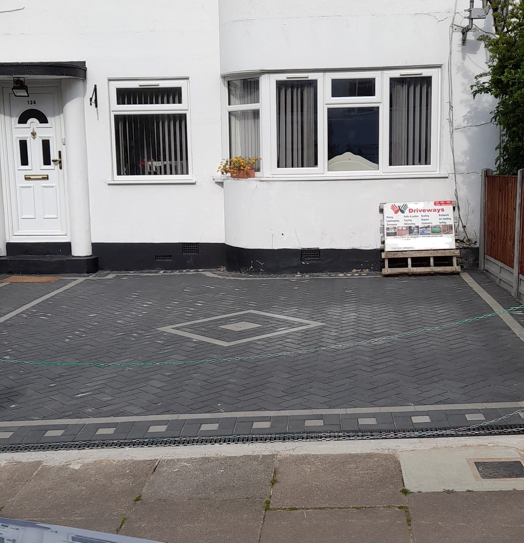 Fully paved front garden with contractor's advertising