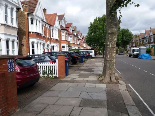 Row of houses with cars parked in front gardens 
