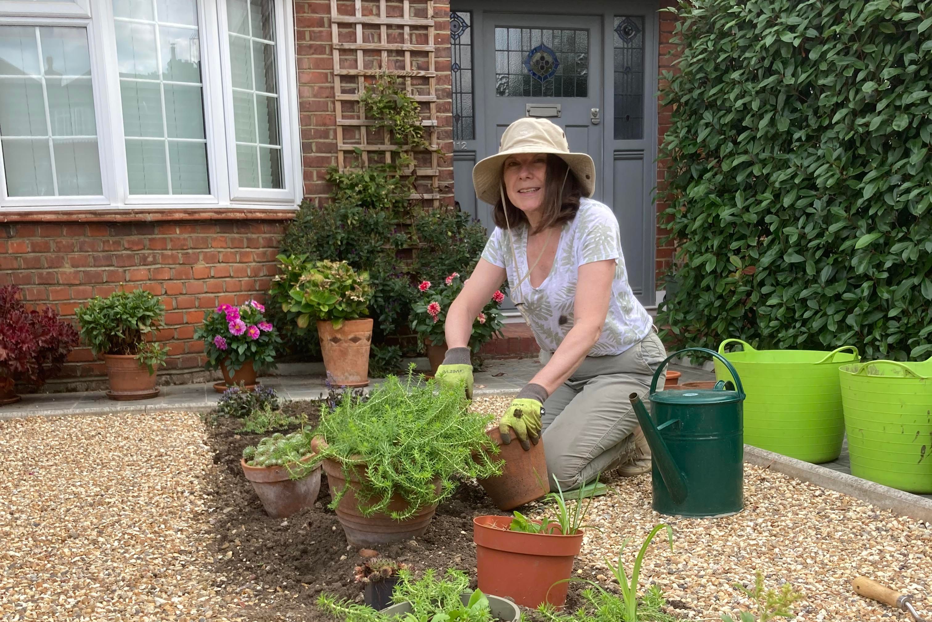 a woman putting plants in a front garden