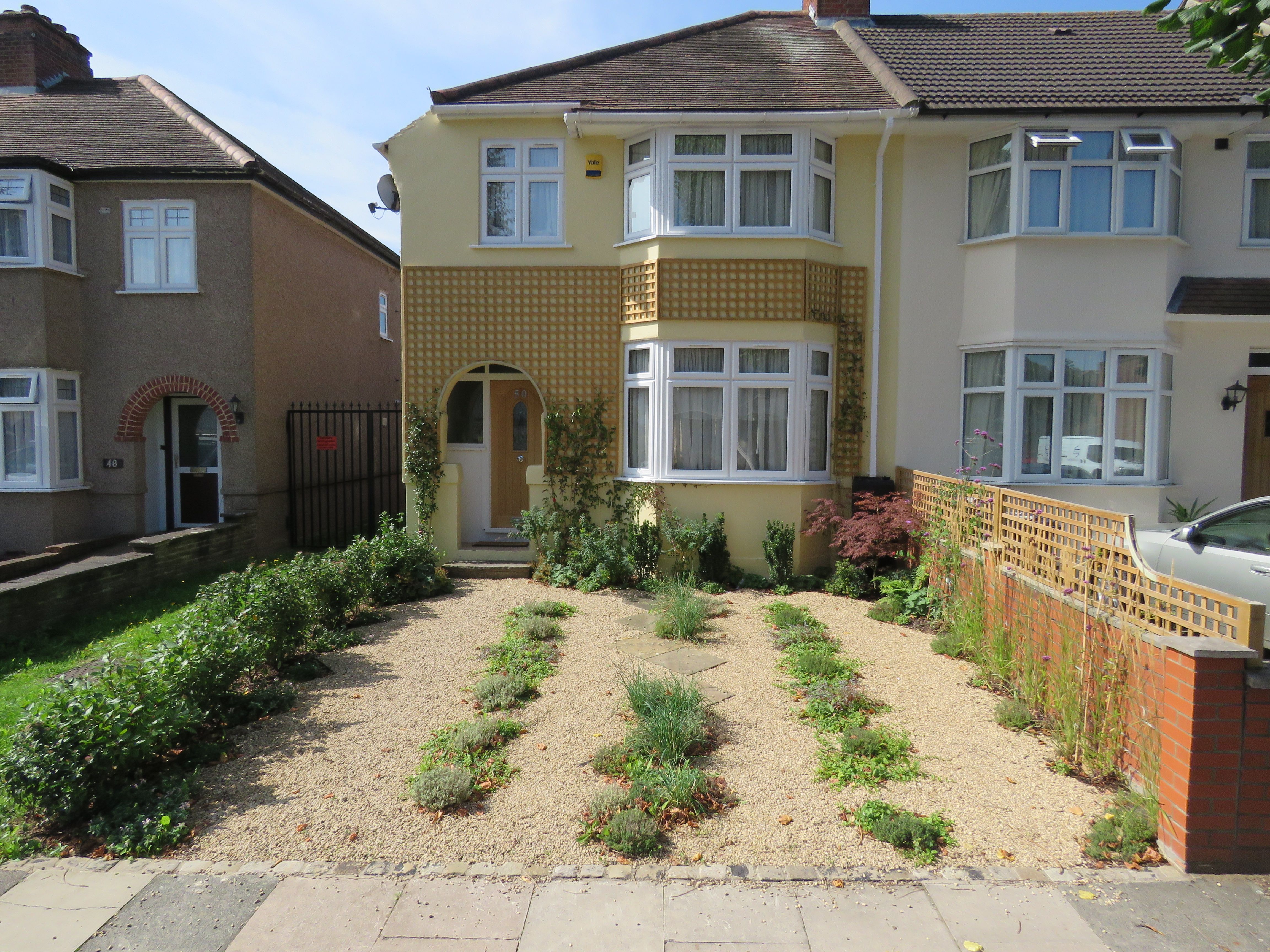 Photo of a depaved and restored front garden in Greenford with space for parking 2 cars on gravel, and plenty of plants.