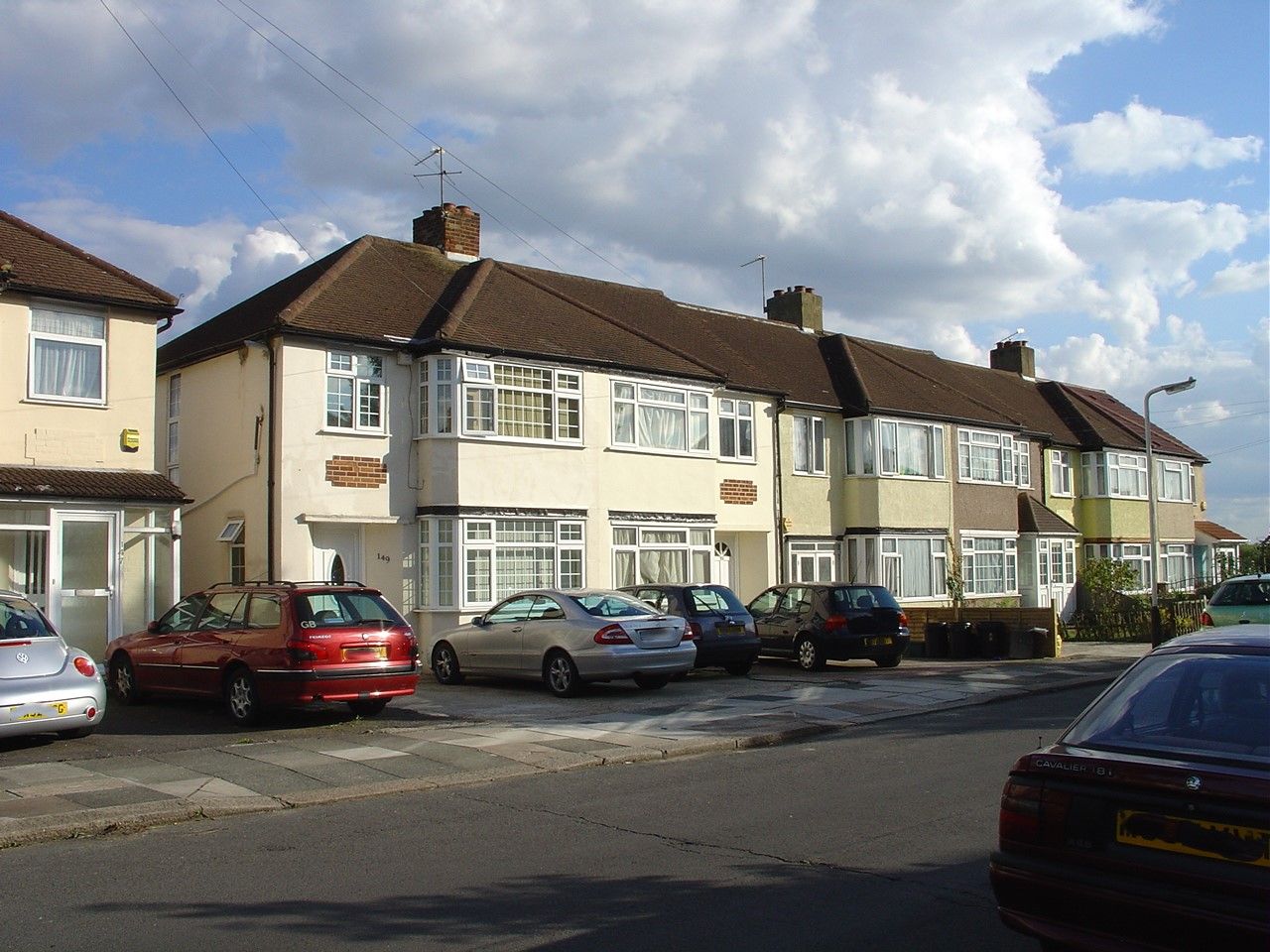 A road with cars parked in front gardens