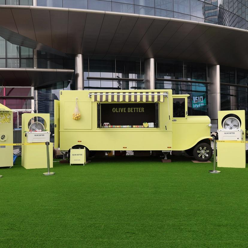 잔디 광장에 설치된 올리브 베러 레몬옐로우 푸드트럭과 파라솔 전경