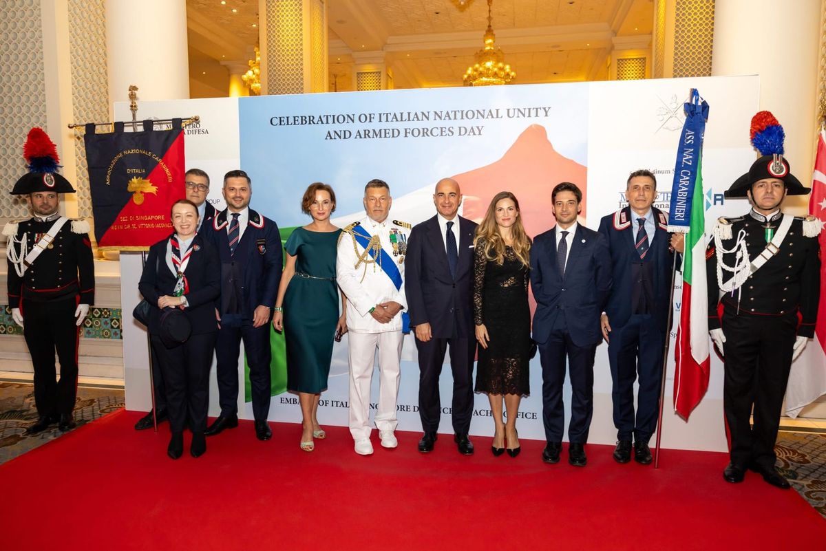 Group photograph on a red carpet in front of a backdrop for the Celebration of Italian National Unity and Armed Forces Day.