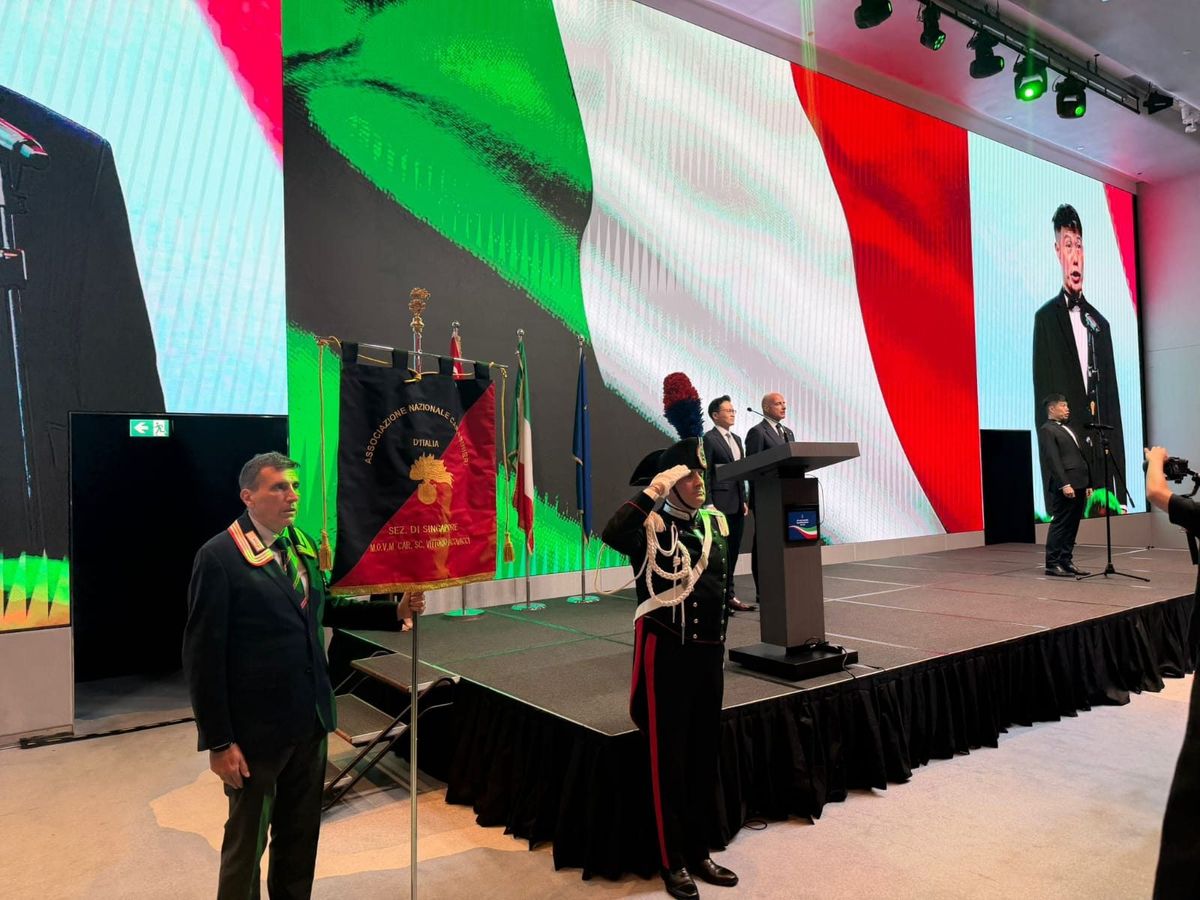 A member holds the section's banner while a Carabiniere in full dress uniform salutes during the Italian national anthem.