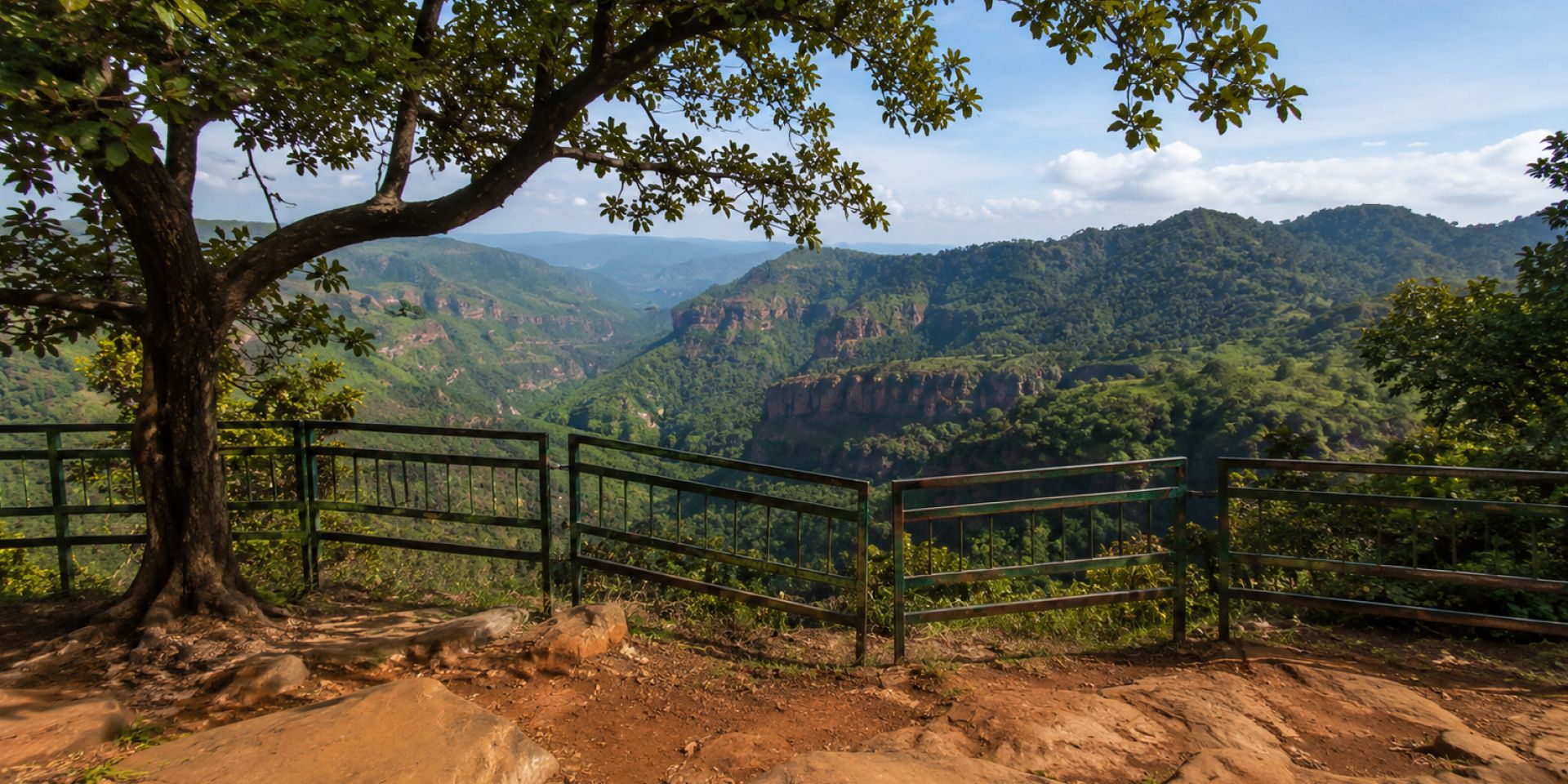 Ancient 5th-century Pandav Caves carved into sandstone hill with manicured garden lawns in Pachmarhi