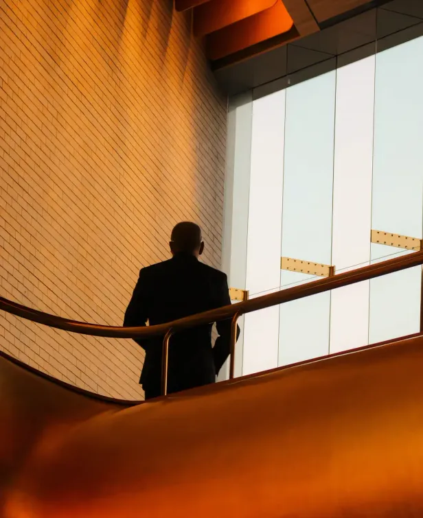 A person walking down a staircase in a light-filled modern building.