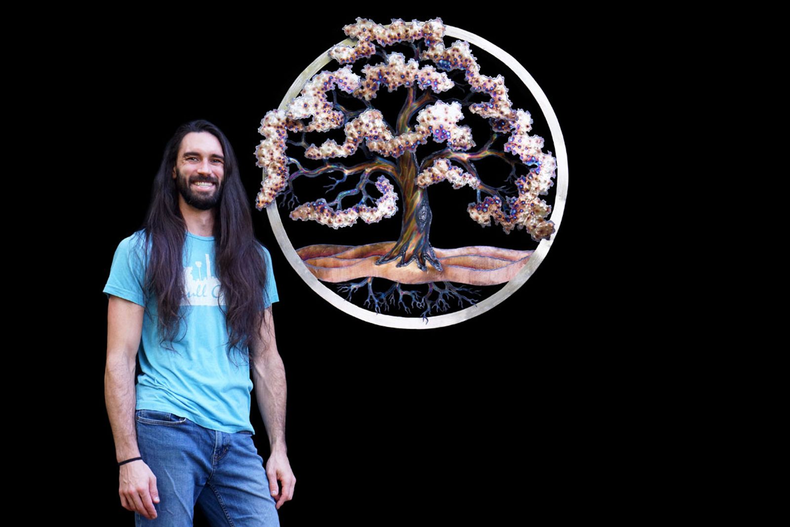 Artist Aiden Dale with his wall hanging metal tree of life sculpture.