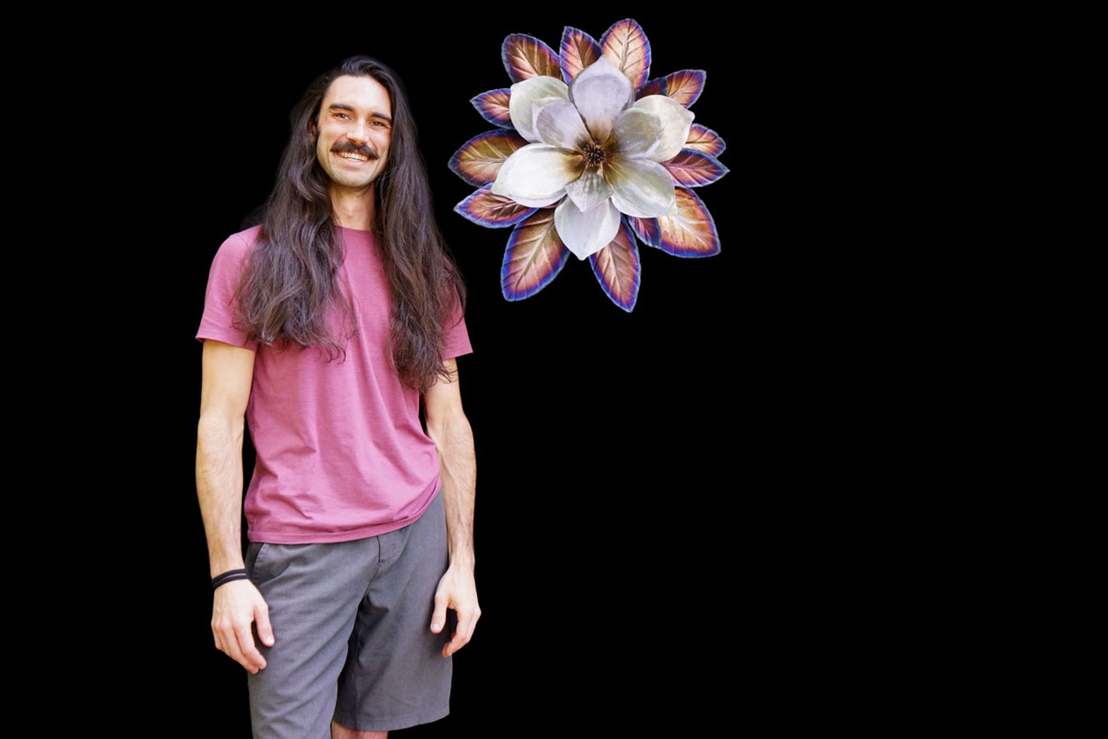 Artist Aiden Dale beside his stainless steel magnolia sculpture, handmade with torch patina and intricate leaf textures.