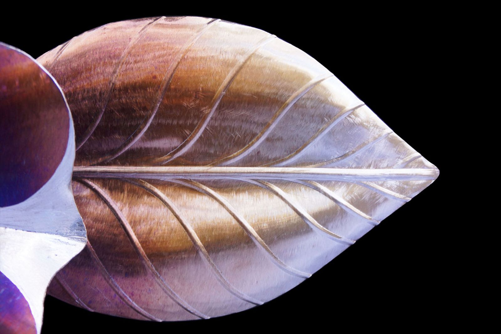 Leaf detail of stainless steel petunia sculpture with bead-rolled veins and torch patina for natural texture.