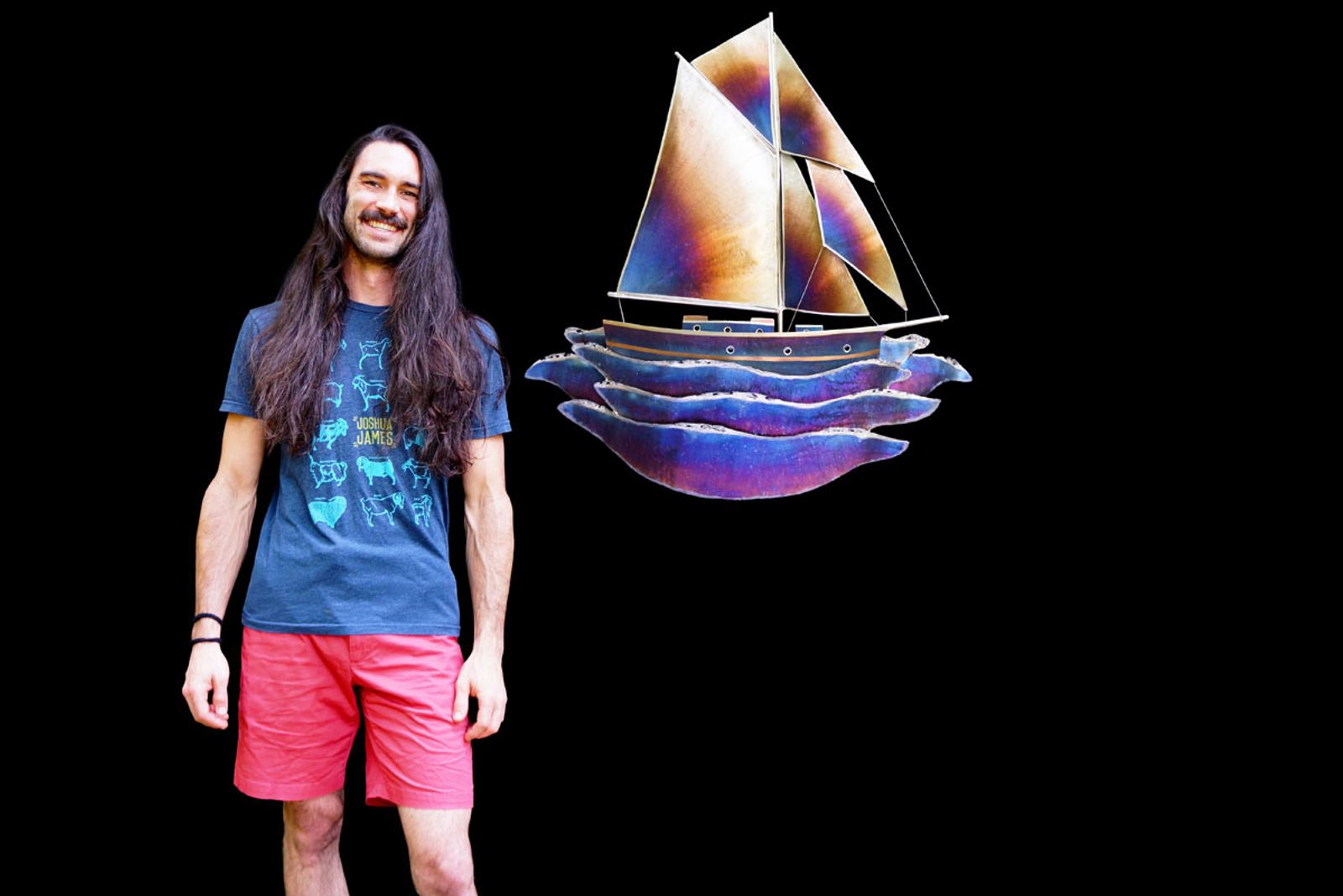 Artist Aiden Dale beside his stainless steel sailboat sculpture, handmade with torch patina and intricate grinder detailing.