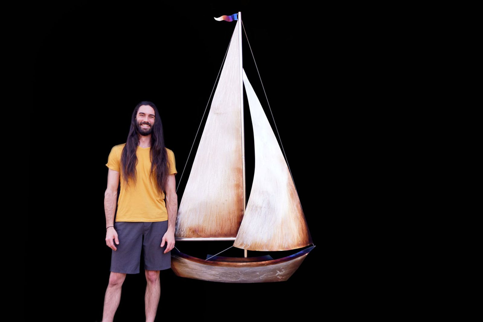 Artist Aiden Dale with his simple metal sailboat sculpture.