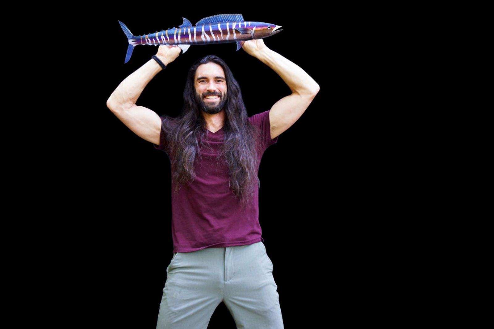 Artist Aiden Dale holding his stainless steel wahoo fish sculpture, handmade sportfish wall art with vivid heat patina.