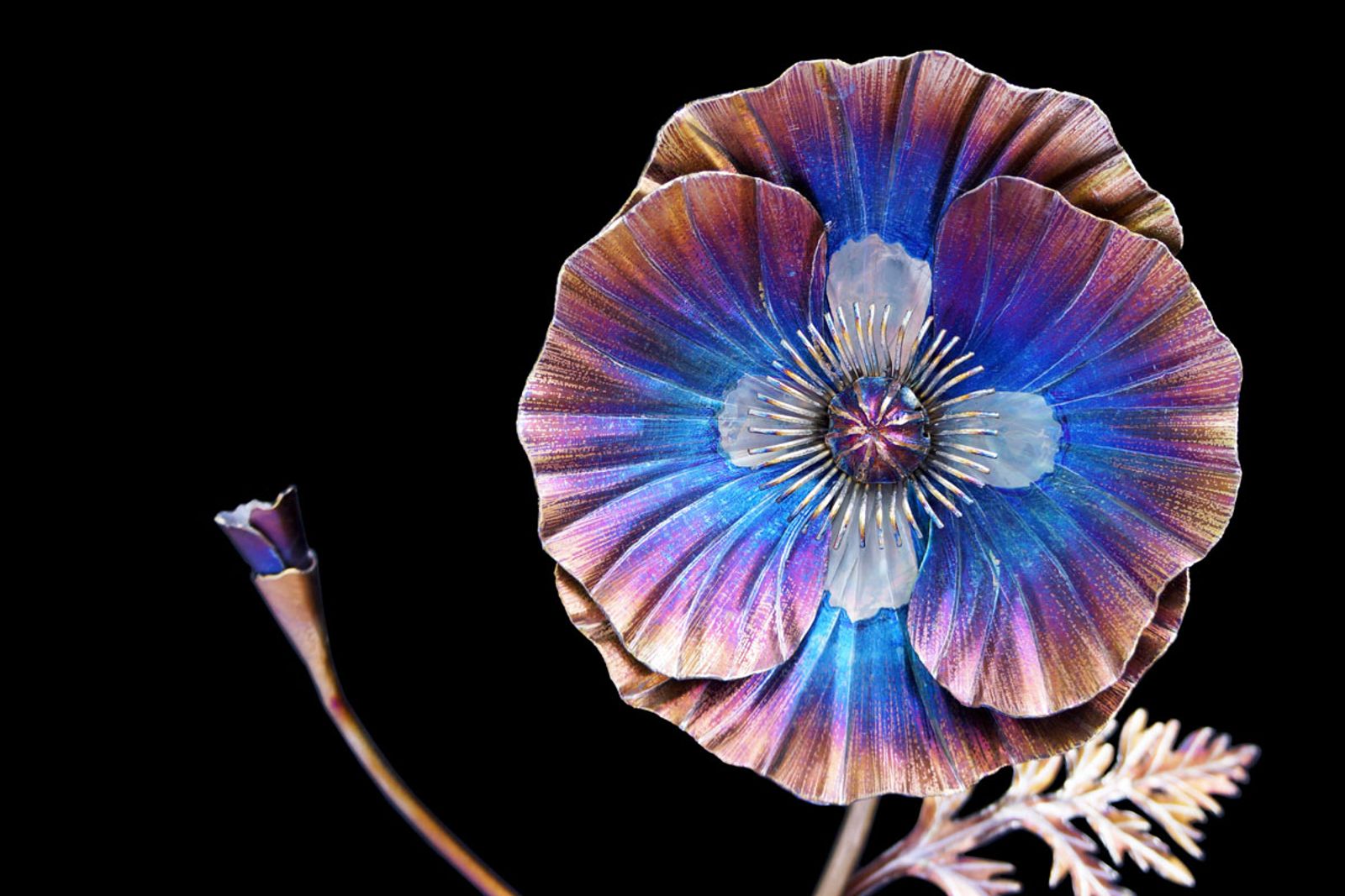 Detailed view of stainless steel poppy bloom with welded bud, torch-colored petals, all is hand-shaped metalwork.