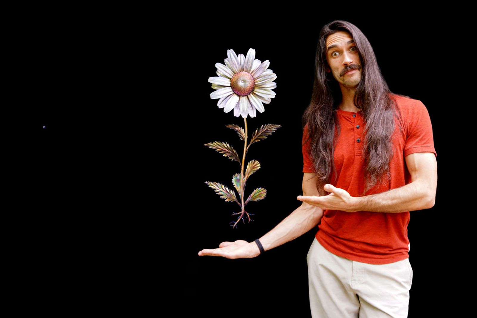 Metal sculptor Aiden Dale beside his stainless steel daisy sculpture with bead-rolled leaves, golden center, and detailed flower form.