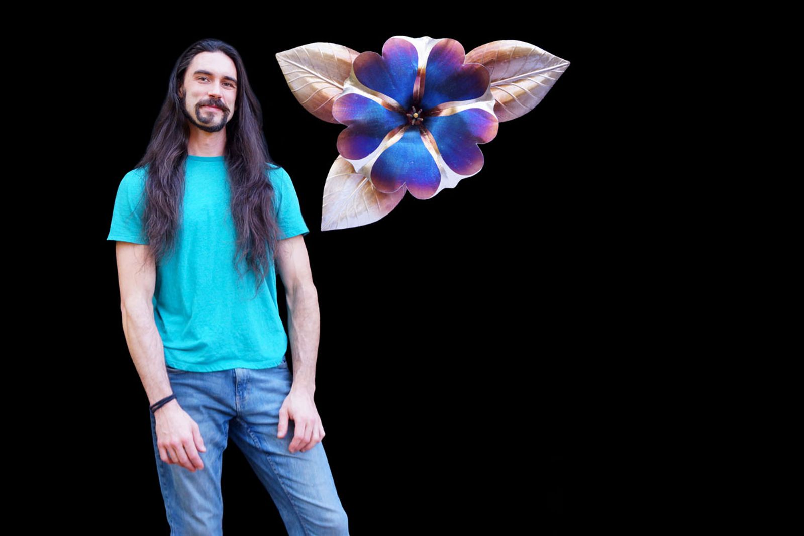 Artist Aiden Dale beside his oversized stainless steel petunia sculpture, handmade with flame patina and detailed grinder work.