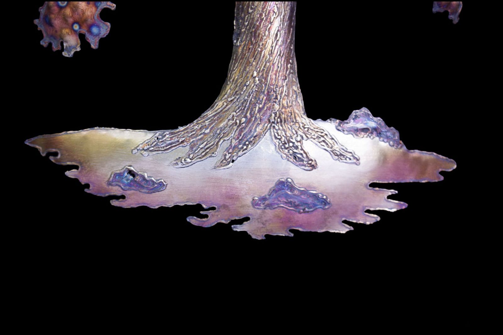 Detail of stainless steel sequoia sculpture showing welded bark trunk, torch-bubbled rock base, and hand-shaped roots.