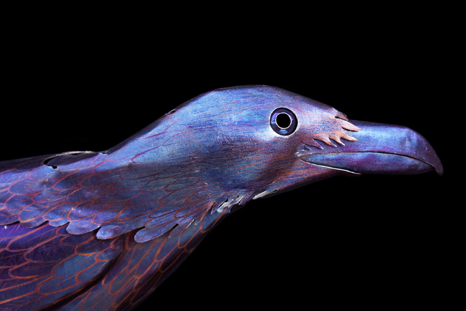 Closeup of metal crow sculptures head.
