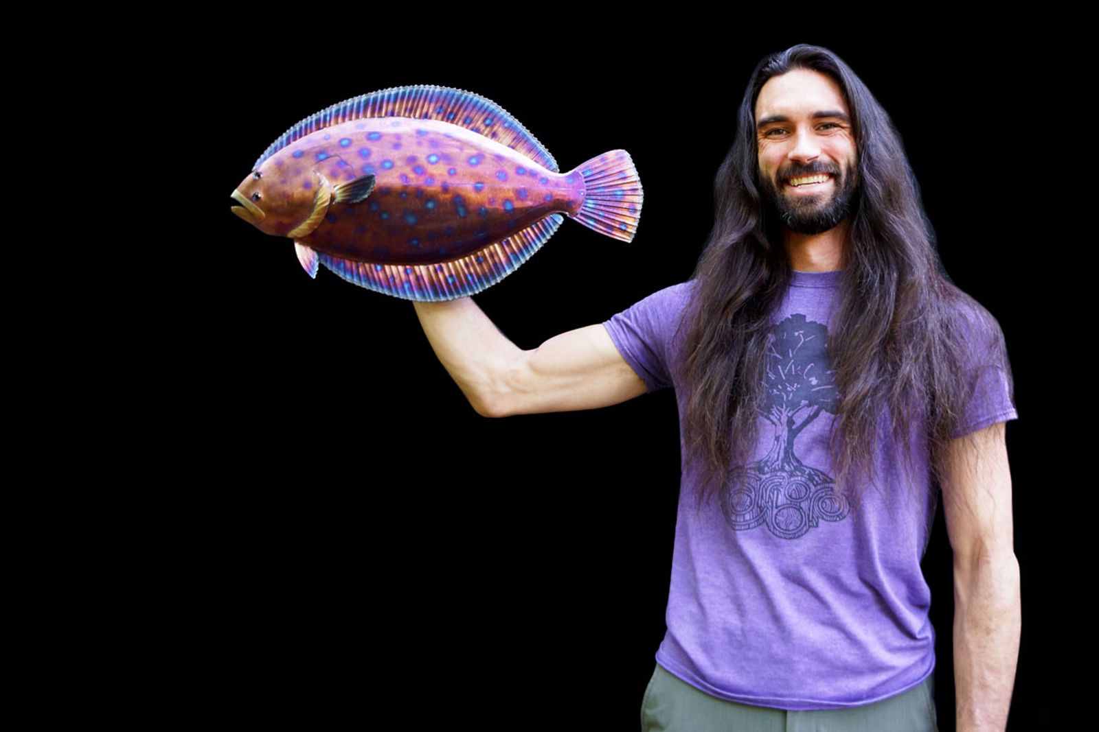 Artist Aiden Dale holding his stainless steel flounder sculpture, flame-painted with vivid patina and detailed with hand-ground accents.