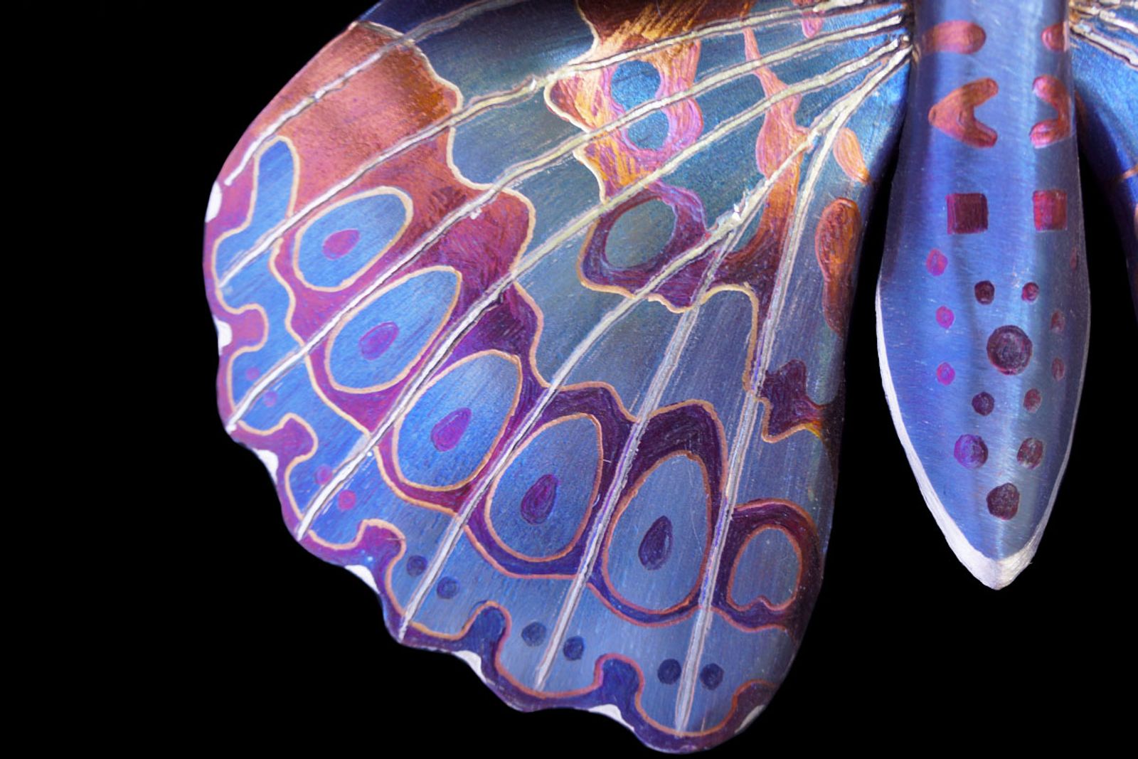 Wings like stained glass: each line and gradient built through hand-grinding and carefully layered torch patina. Stainless steel transformed into something delicate and wild.