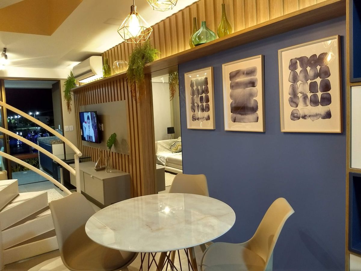 Sala de jantar com mesa redonda de mármore e tríptico sobre parede azul