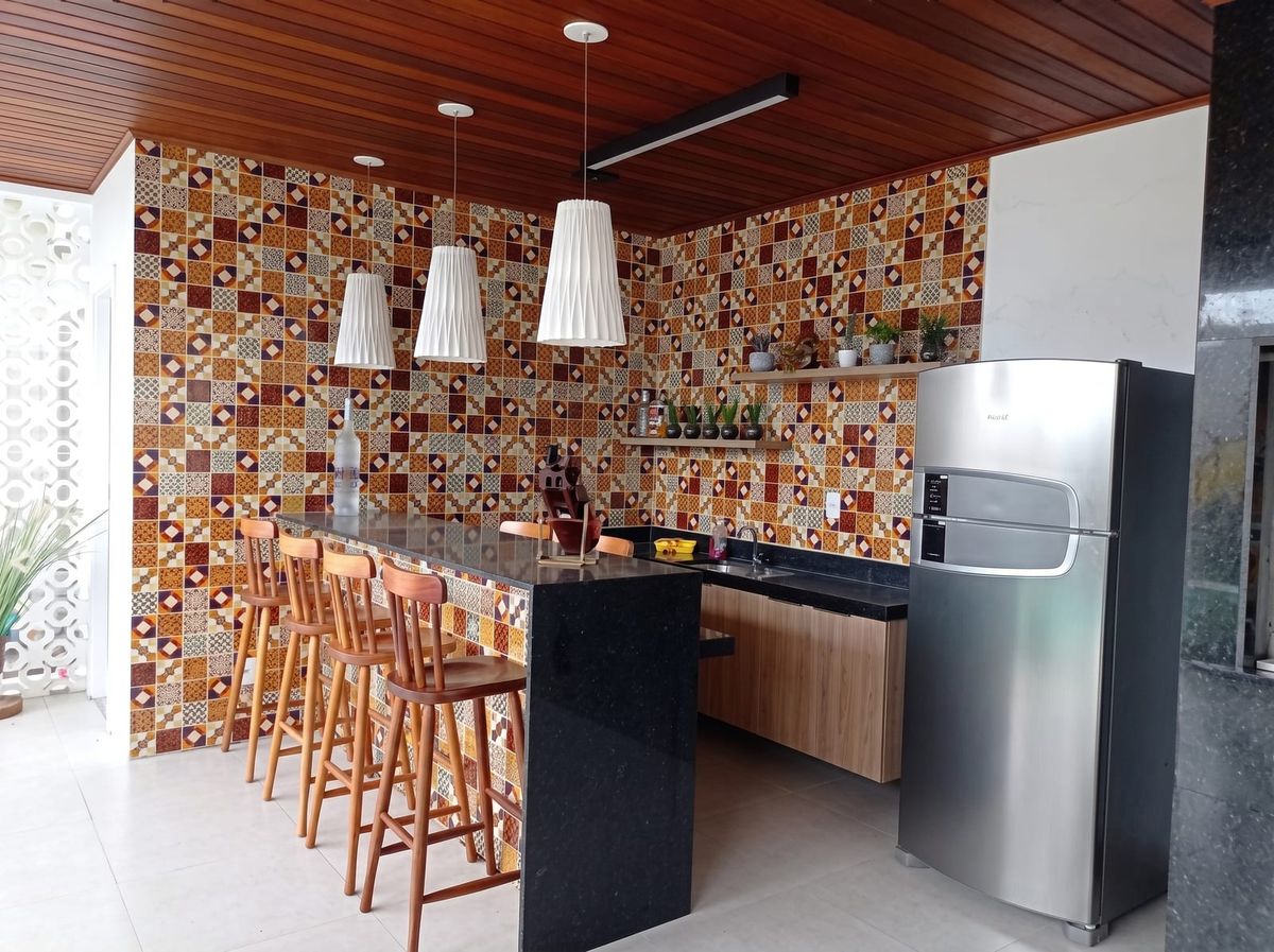 Espaço gourmet com bancada, revestimento colorido e forro de madeira